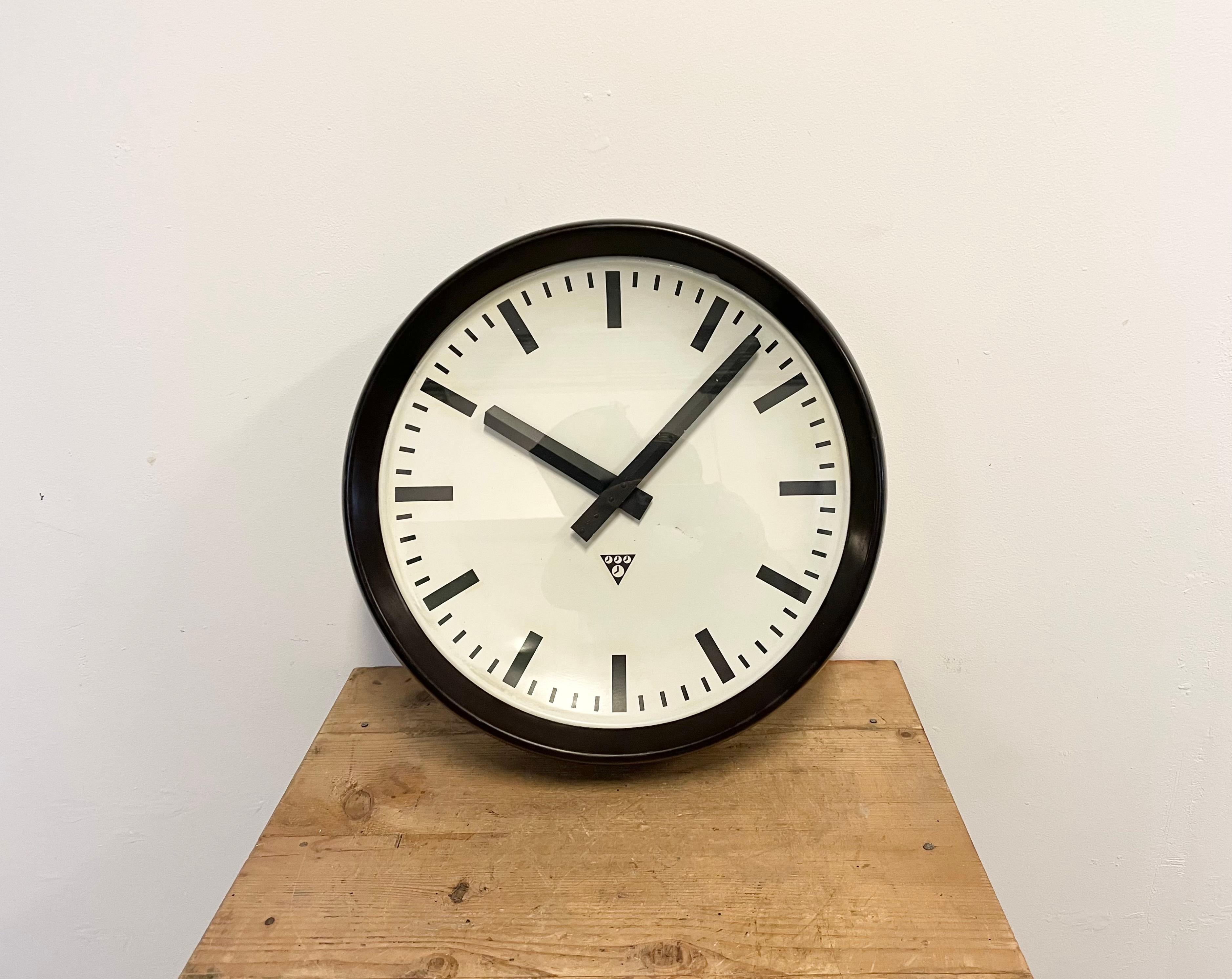 This large wall clock was produced by Pragotron in former Czechoslovakia during the 1960s. It features a brown bakelite frame, an aluminium dial, an aluminium hands and a clear glass cover. The piece has been converted into a battery-powered