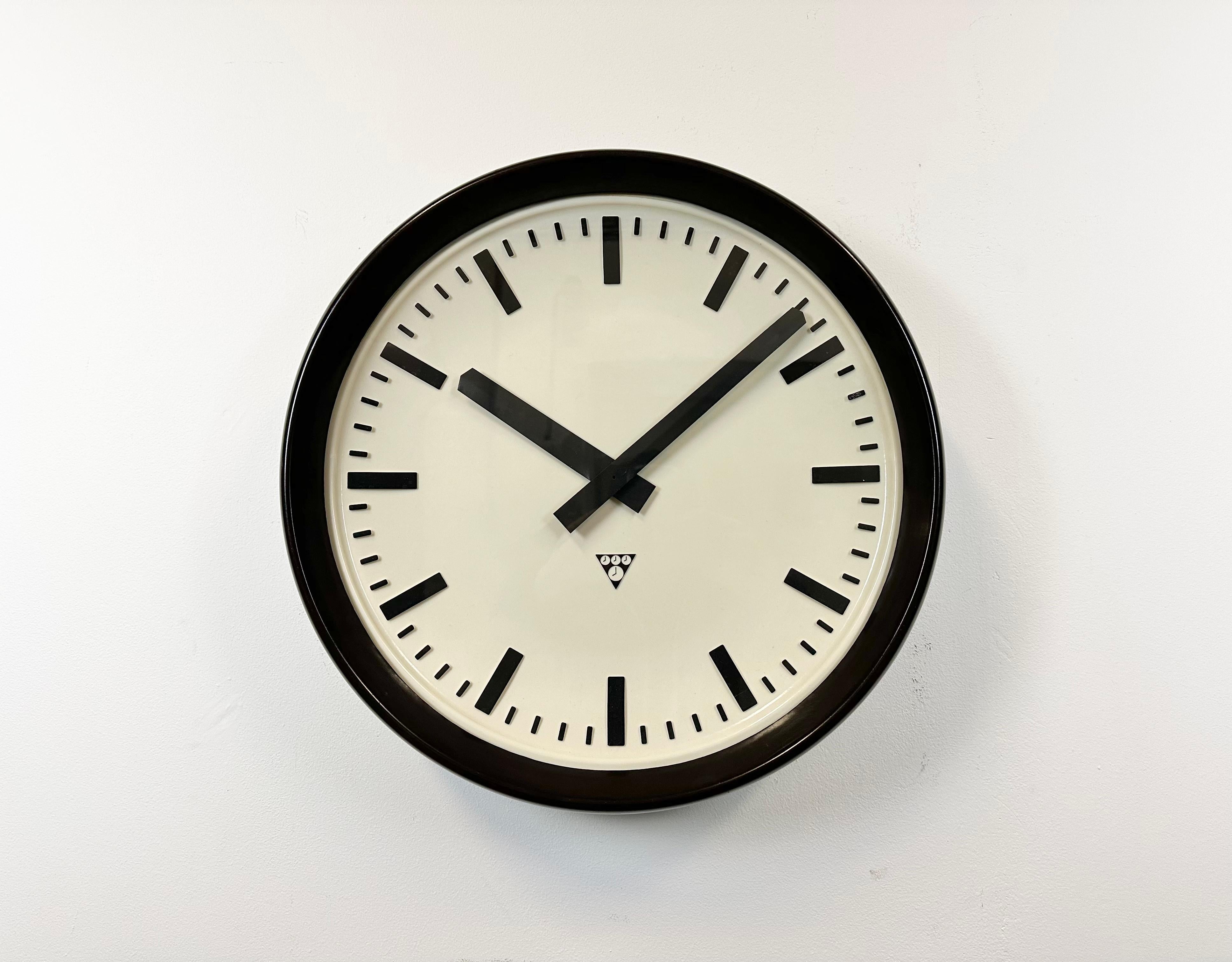 This large wall clock was produced by Pragotron in former Czechoslovakia during the 1960s. It features a brown bakelite frame, a white bakelite dial, an aluminium hands, a clear glass cover and brown bakelite back.The piece has been converted into a