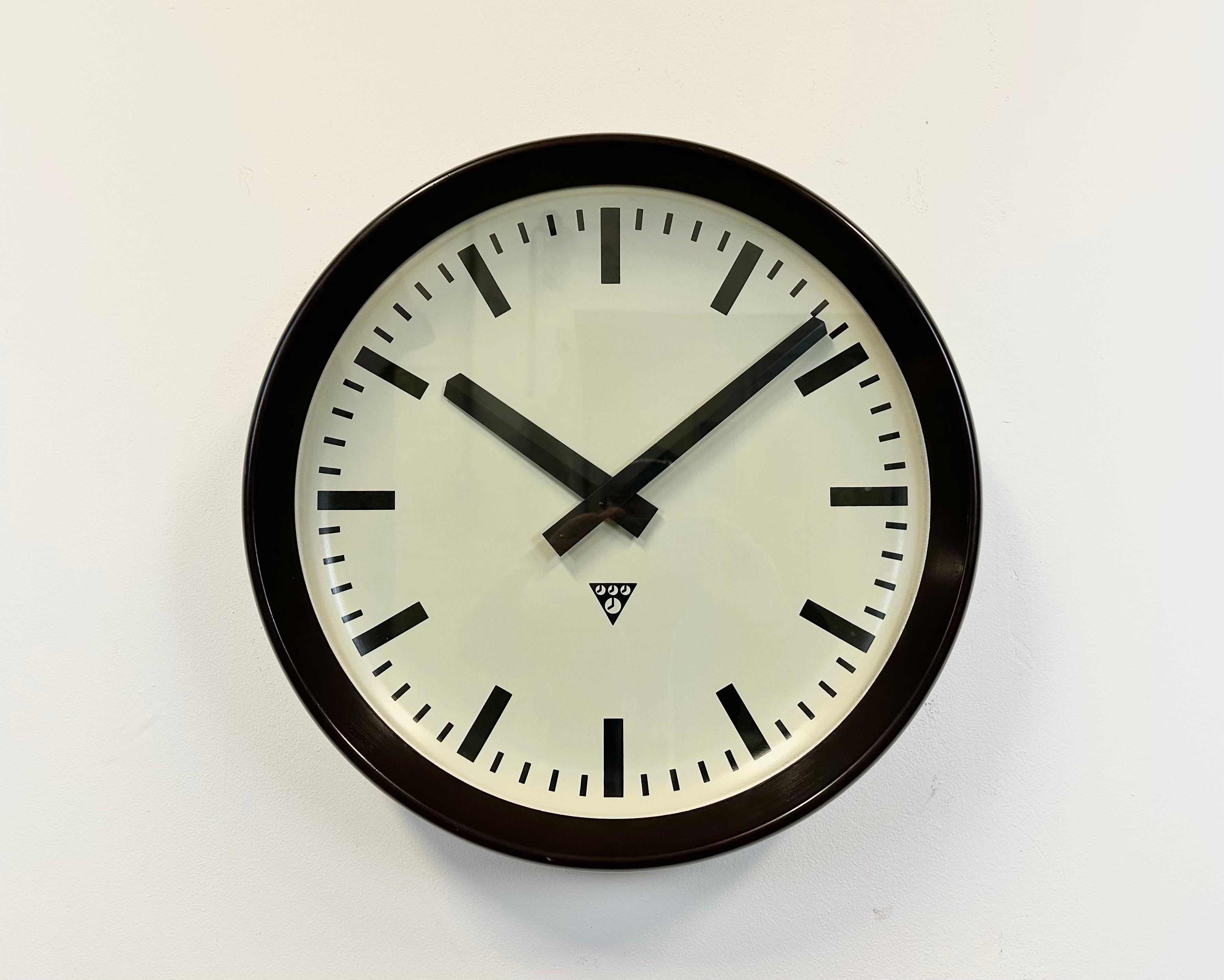 This large wall clock was produced by Pragotron in former Czechoslovakia during the 1960s. It features a brown bakelite frame, a metal dial, an aluminium hands and a clear glass cover. The piece has been converted into a battery-powered clockwork