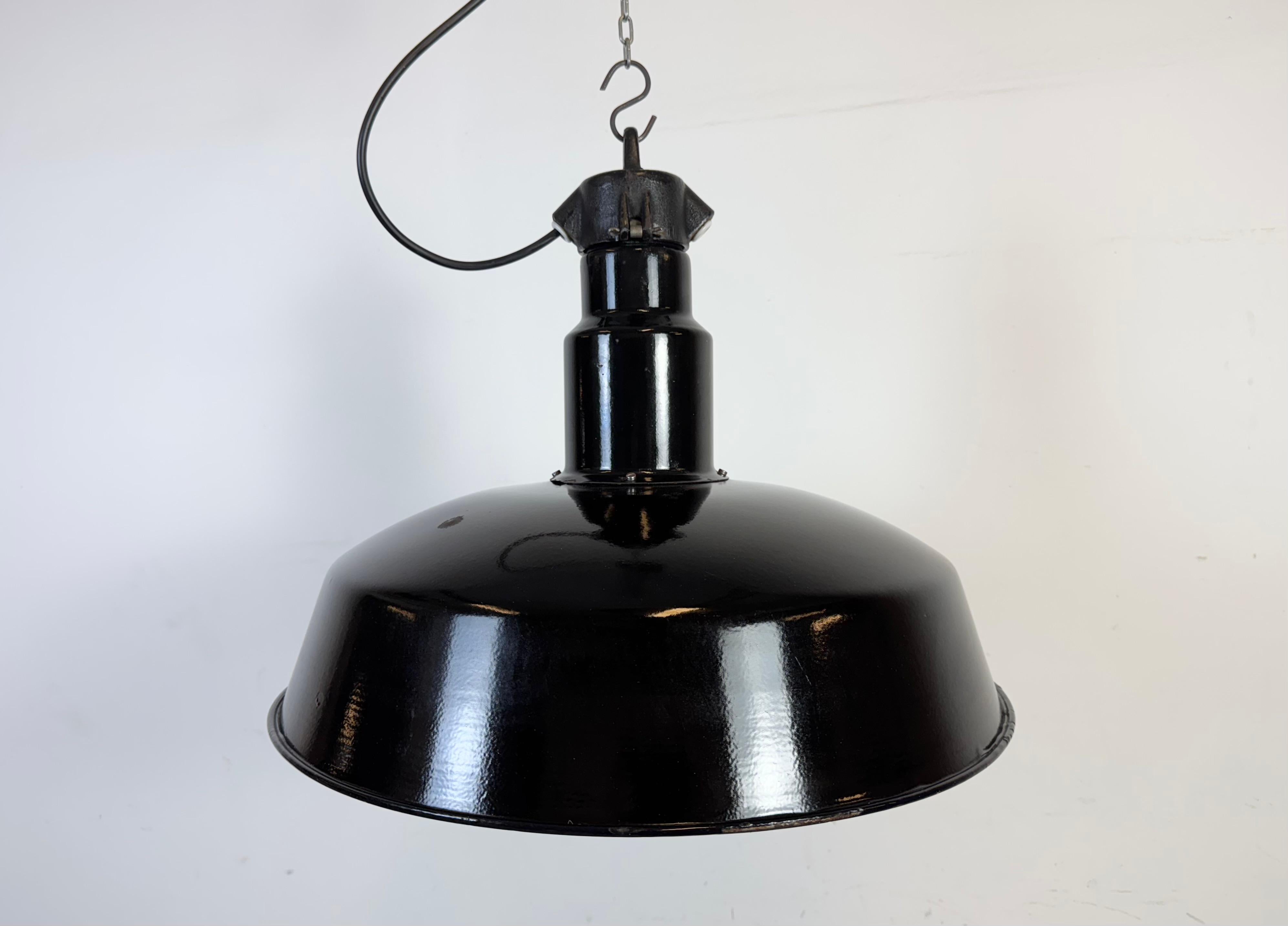 Lampada a sospensione industriale in smalto nero realizzata da Elektrosvit nell'ex Cecoslovacchia negli anni Cinquanta. Smalto bianco all'interno del paralume. Piano in ghisa. L'attacco originale con riduzione richiede lampadine standard E 27/ E26.