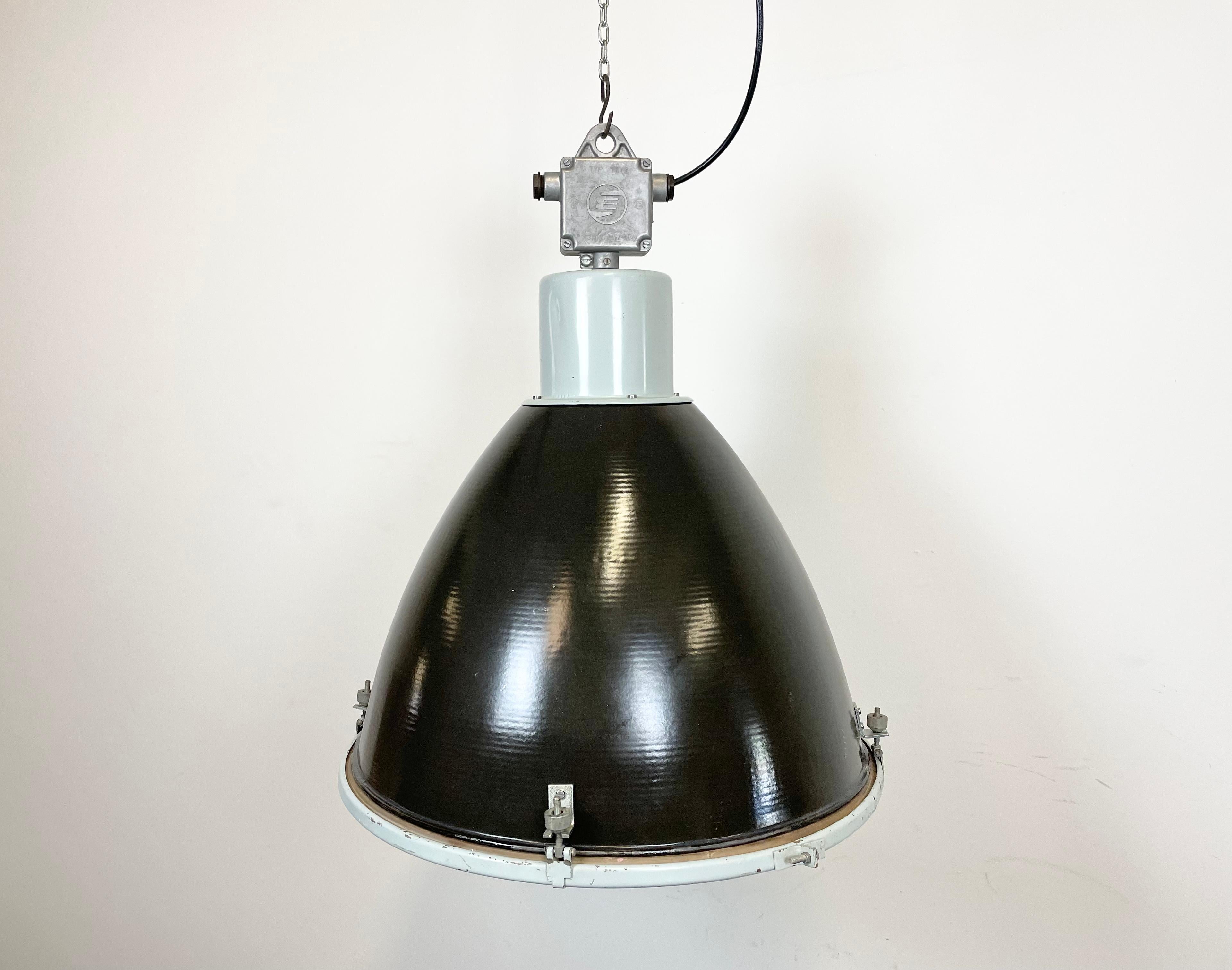 Industrial black enamel pendant lamp designed and produced by Elektrosvit in former Czechoslovakia during the 1960s. It features a grey metal top with cast aluminium box, a black enamel shade with white enamel interior and a clear glass cover.
New