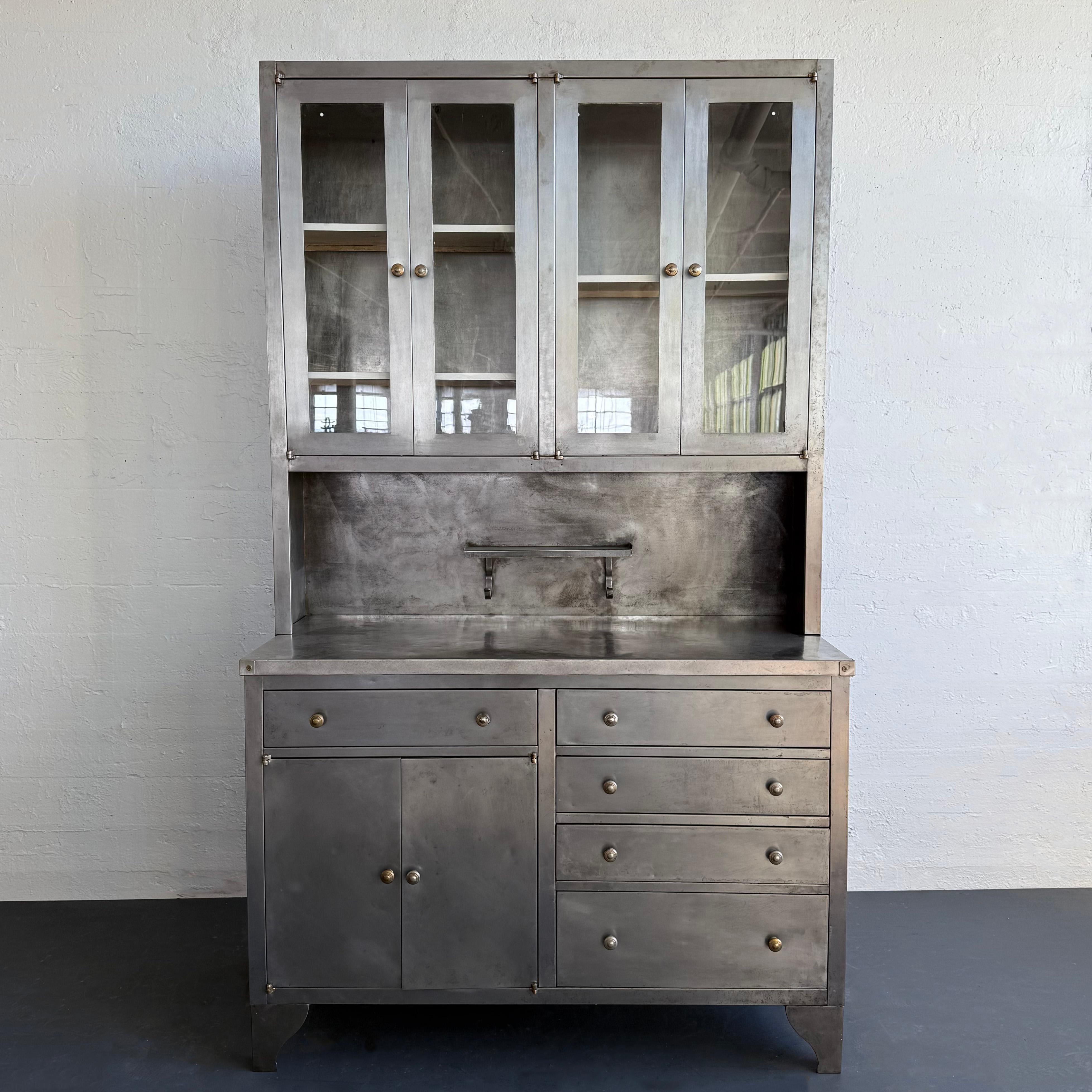 This early 20th century, industrial oversized freestanding apothecary hoosier cabinet is two parts comprised of reinforced folded and pressed 