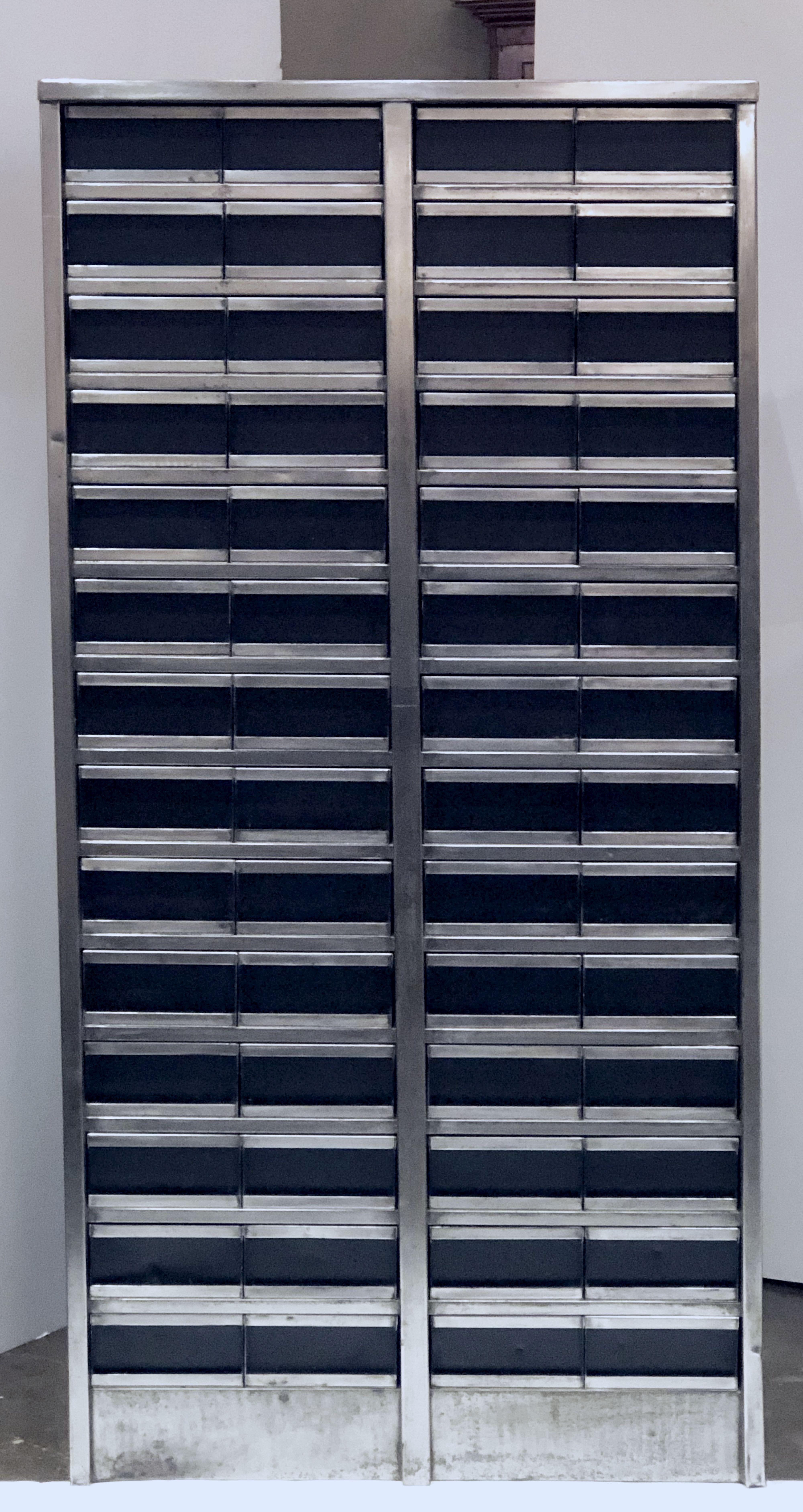 A fine large English industrial cabinet of burnished steel featuring (56) small half-drawers for storage, set into four vertical rows of (14) drawers, each drawer with pull handle. 

Dimensions: H 69 1/2 inches x W 34 1/2 inches.

 