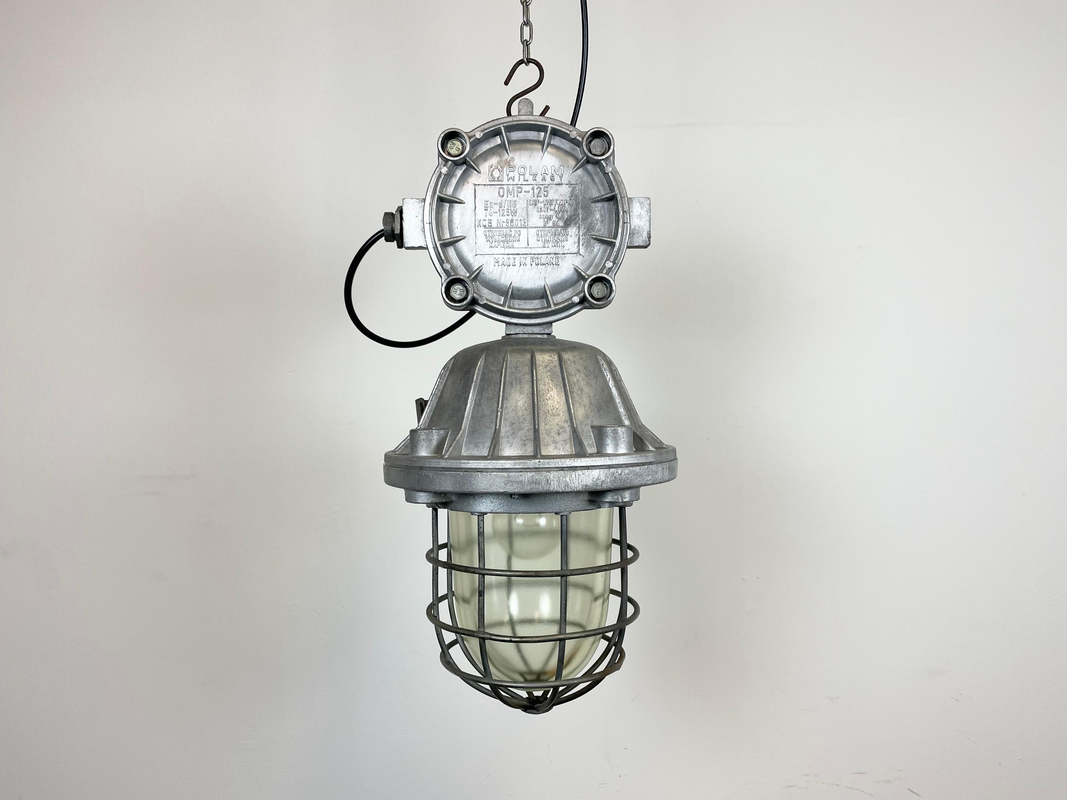 Large industrial factory hanging lamp made by Polam Wilkasy in Poland during the 1970s. It features a cast aluminium body, a clear glass cover and iron grid. The porcelain socket requires E 27 lightbulbs. New wire. The weight of the lamp is 8 kg !!!!