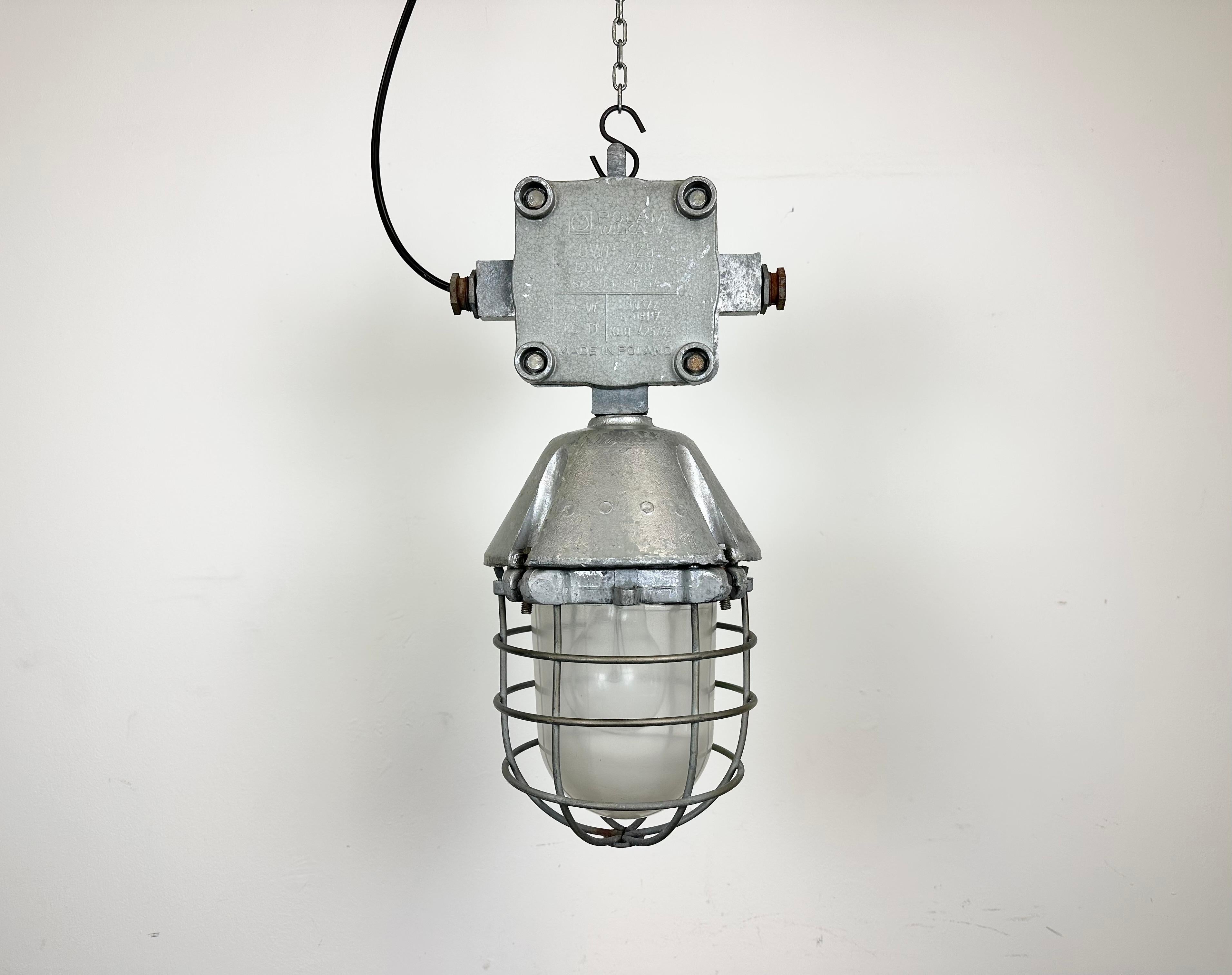 Large industrial factory hanging lamp made by Polam Wilkasy in Poland during the 1960s. It features a cast aluminium body, a clear glass cover and iron grid. The porcelain socket requires standard E 27/ E 26 lightbulbs. New wire. The weight of the