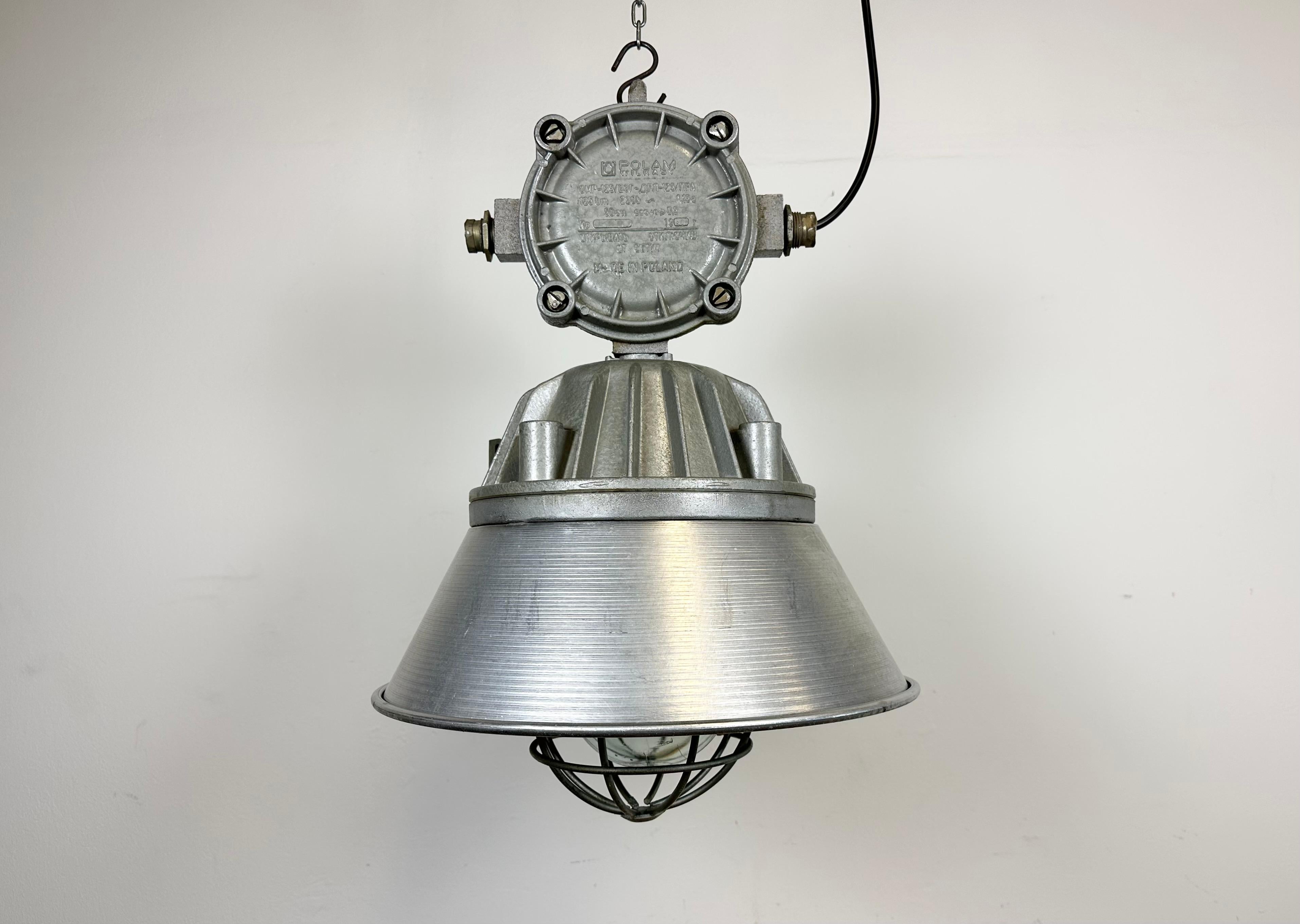 Large industrial factory hanging lamp made by Polam Wilkasy in Poland during the 1970s. It features a cast aluminium body, an aluminium shade,a clear glass cover and iron grid. The porcelain socket requires E 27/ E26 lightbulbs. New wire. The weight
