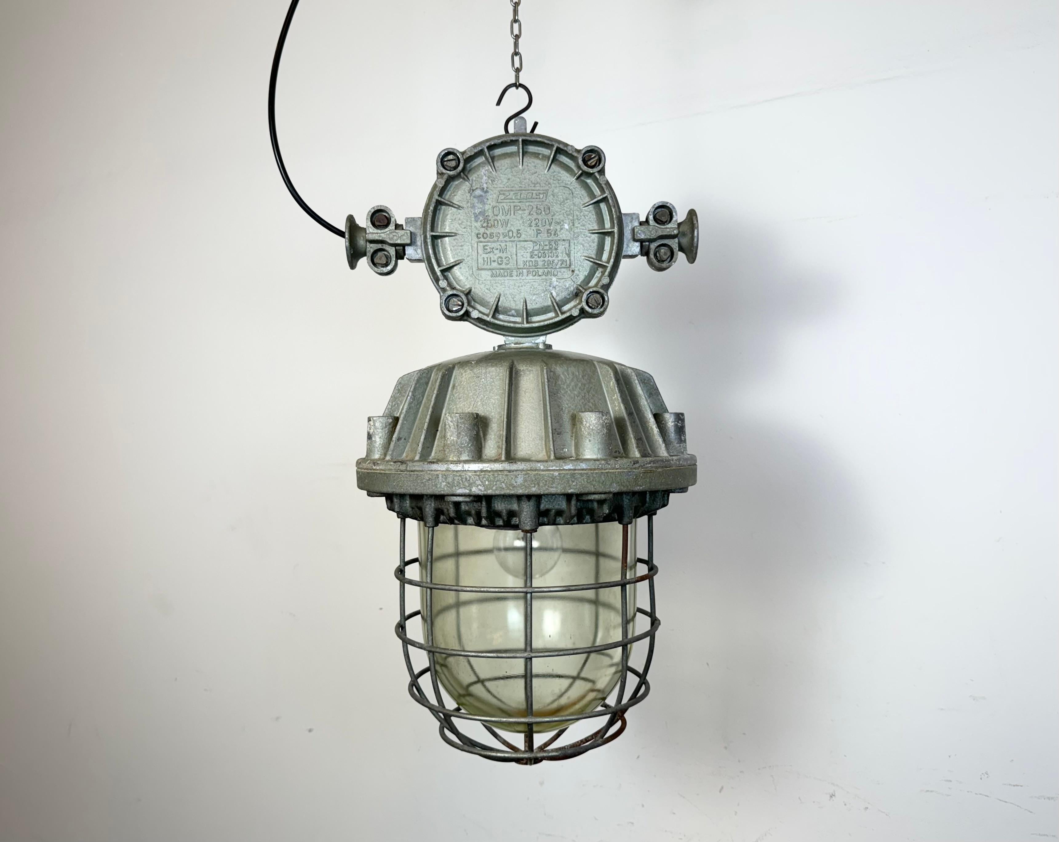Large industrial factory hanging lamp made by Zaos in Poland during the 1970s. It features a cast aluminium body, a clear glass cover and iron grid. The porcelain socket requires E 27/ E 26 lightbulbs. New wire. The weight of the lamp is 16 kg.