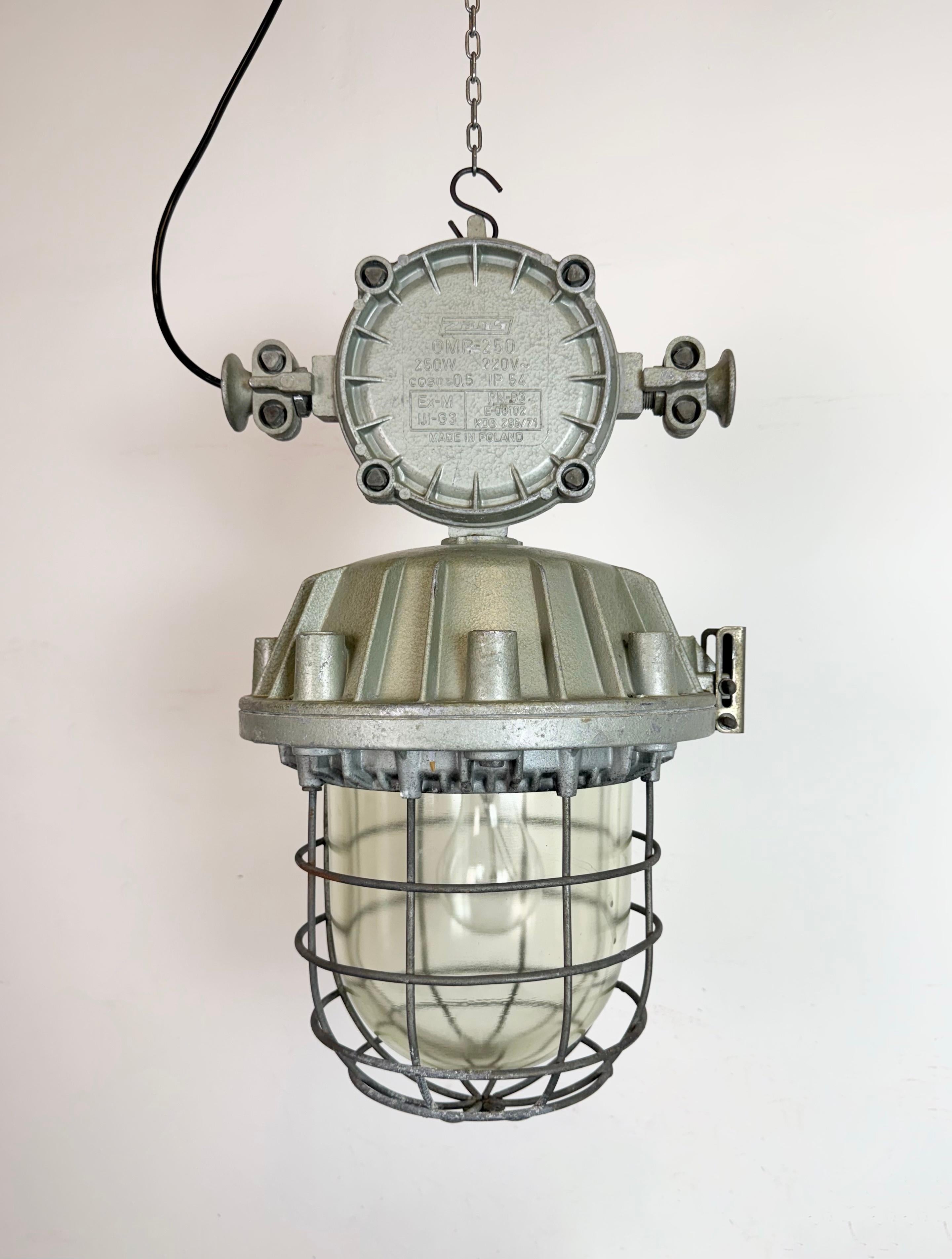 Gran lámpara colgante de fábrica industrial fabricada por Zaos en Polonia durante la década de 1970. Tiene un cuerpo de aluminio fundido, una tapa de cristal transparente y una rejilla de hierro. El casquillo de porcelana requiere bombillas E 27/ E