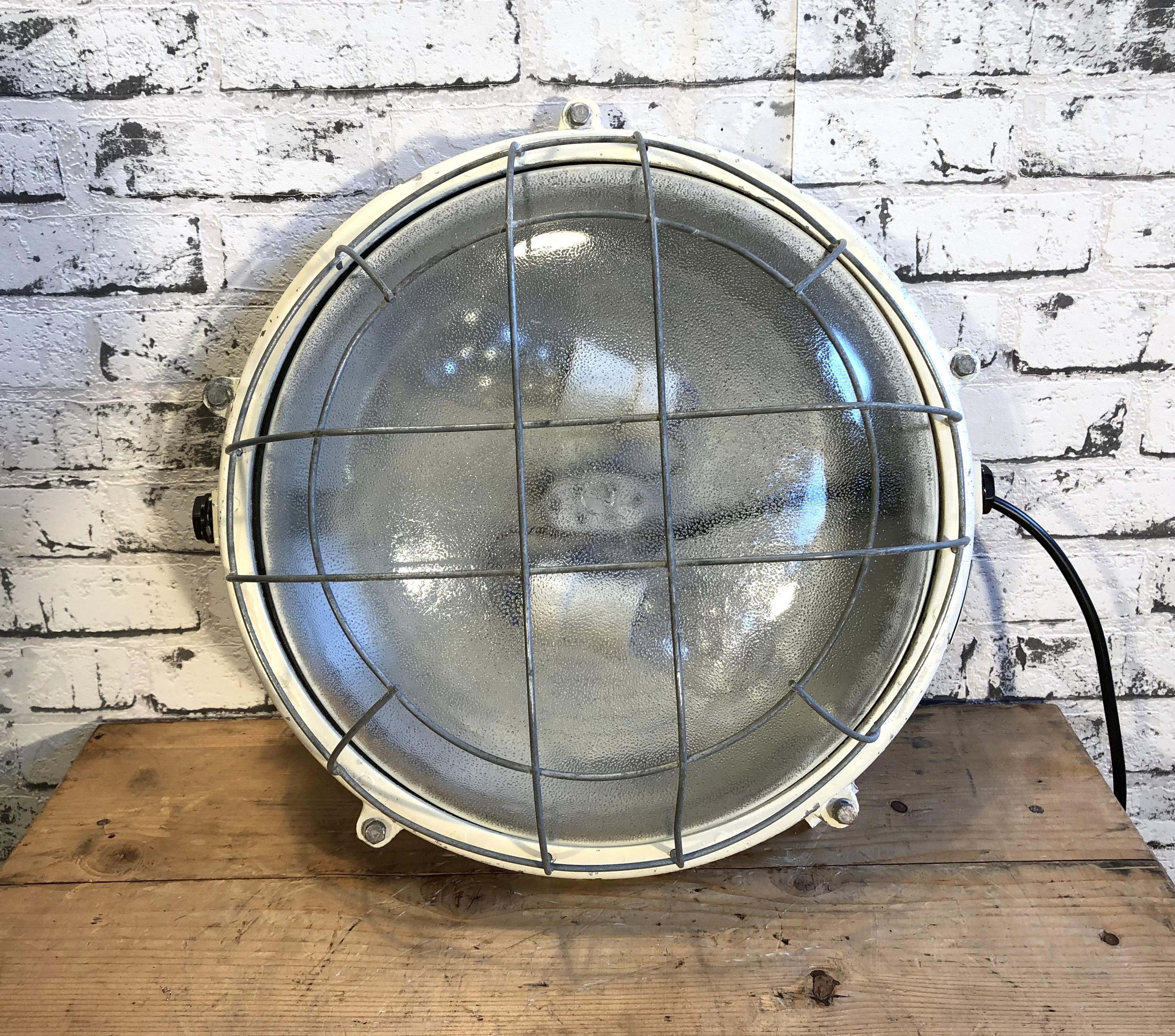 This cast aluminium wall lamp was made by Elektrosvit in former Czechoslovakia during the 1970s.It features cast aluminium body, a frosted curved glass and a steel grid. It can also be used as a ceiling lamp. It has two porcelain sockets for E 27