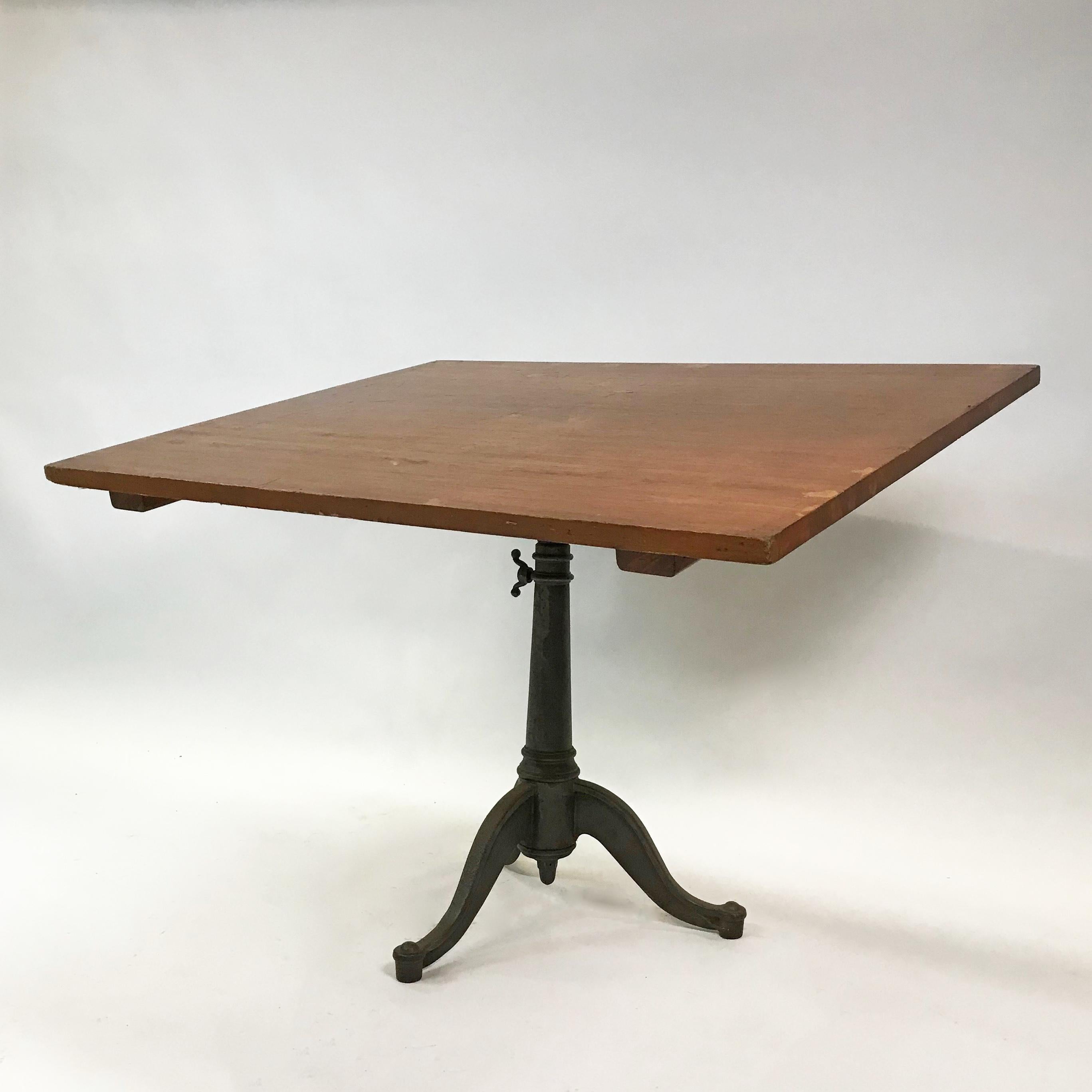 Large, Industrial drafting table features a cherry top with cast iron, pedestal base that is height adjustable from 30 - 38 inches and tilt adjustable from horizontal to vertical. Drafting stool shown is sold separately.