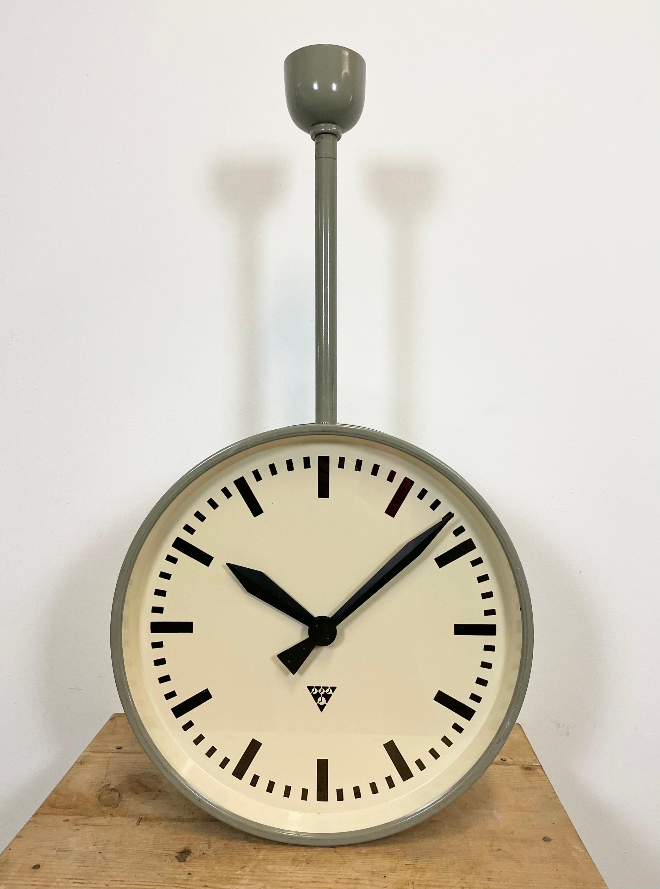 This large double-sided railway or factory clock was produced by Pragotron, in former Czechoslovakia, during the 1950s. The piece features a grey metal body and a clear glass cover. The clock has been converted into a battery-powered clockwork and