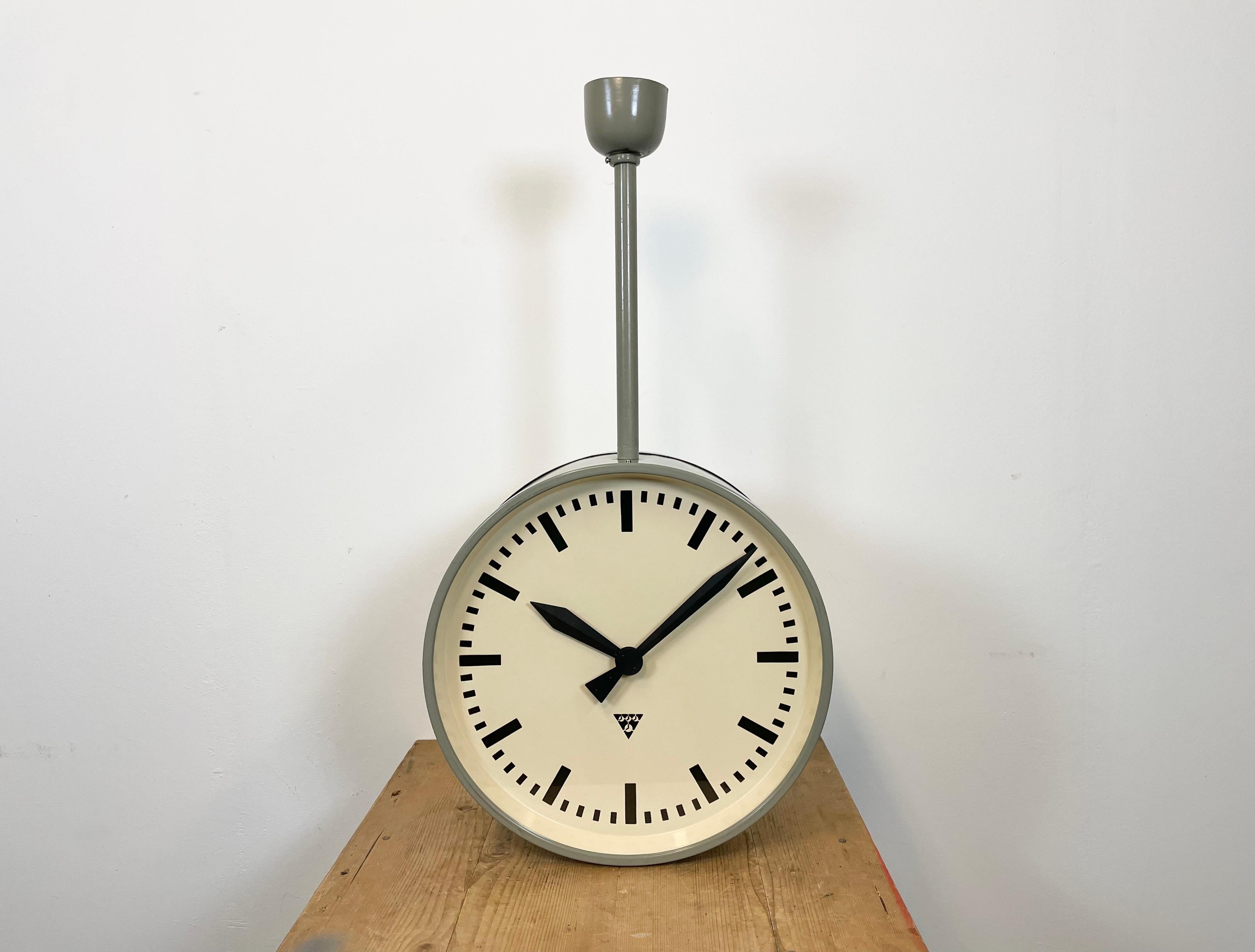 This large double-sided railway or factory clock was produced by Pragotron, in former Czechoslovakia, during the 1950s. The piece features a grey metal body and a clear glass cover. The clock has been converted into a battery-powered clockwork and