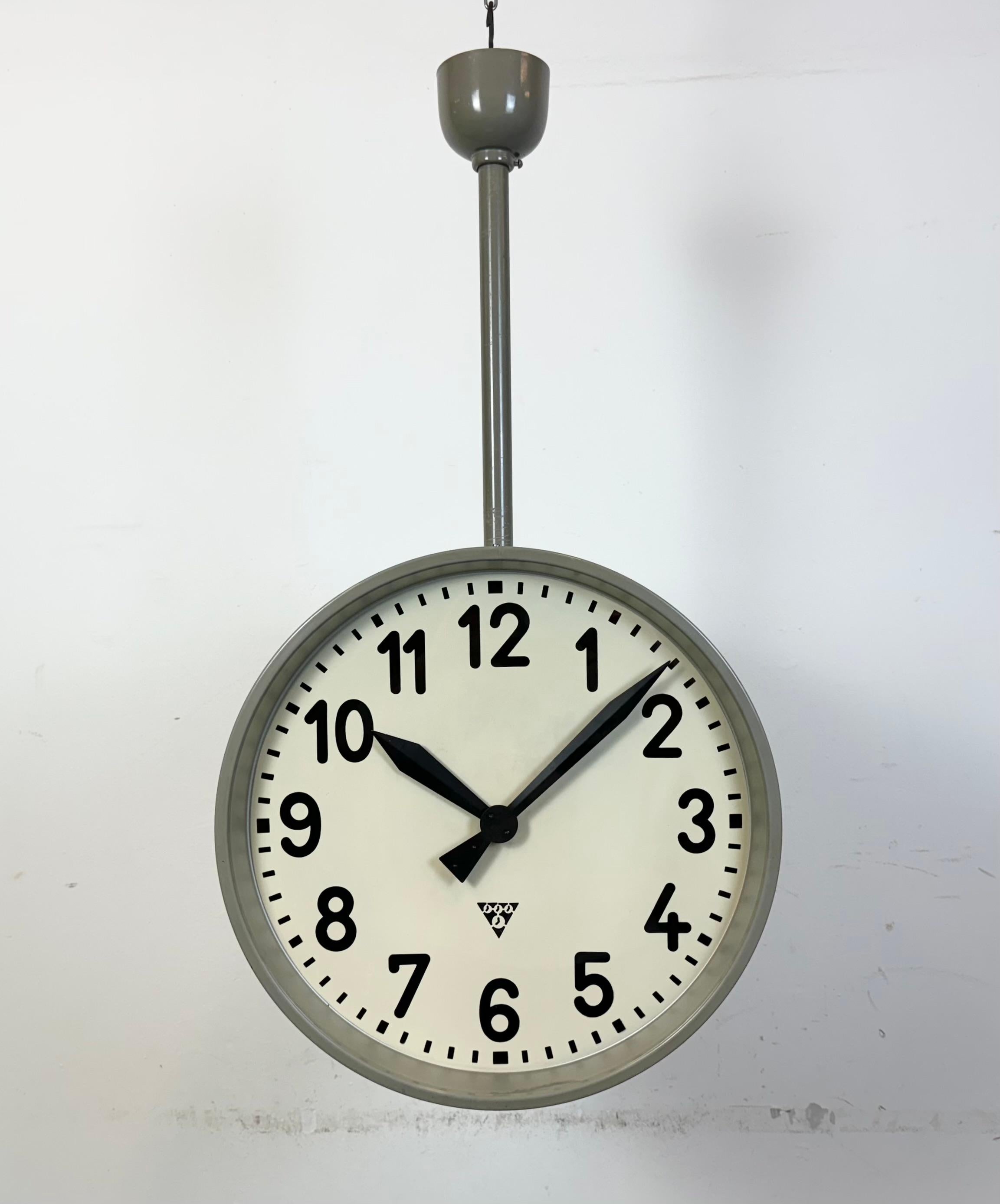 This large double sided railway or factory clock was produced by Pragotron, in former Czechoslovakia, during the 1950s. The piece features a grey hammer paint metal body and a clear glass cover. The clock has been converted into a battery-powered