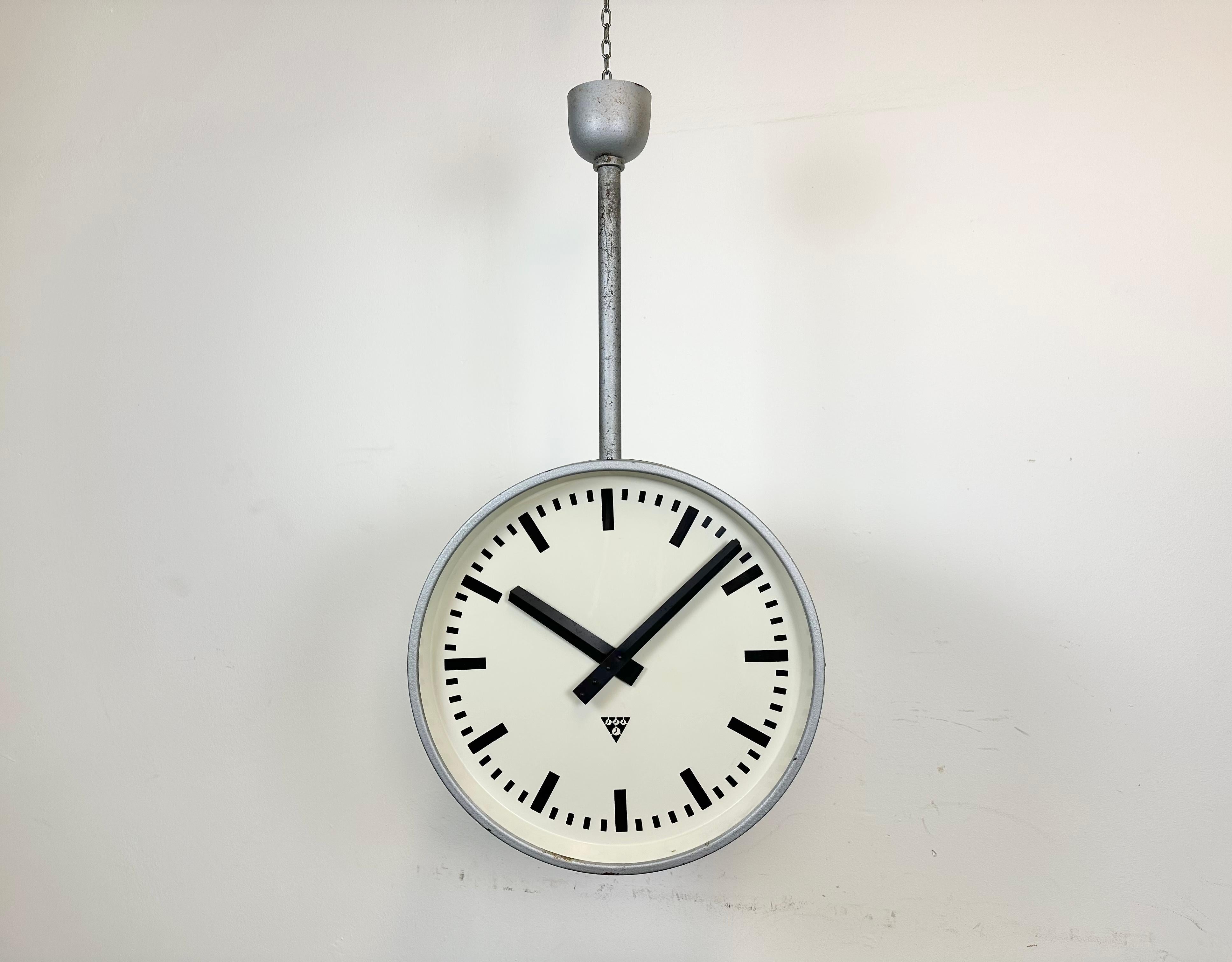 This large double-sided railway or factory clock was produced by Pragotron, in former Czechoslovakia, during the 1960s. The piece features a grey hammer paint metal body and a clear glass cover. The clock has been converted into a battery-powered