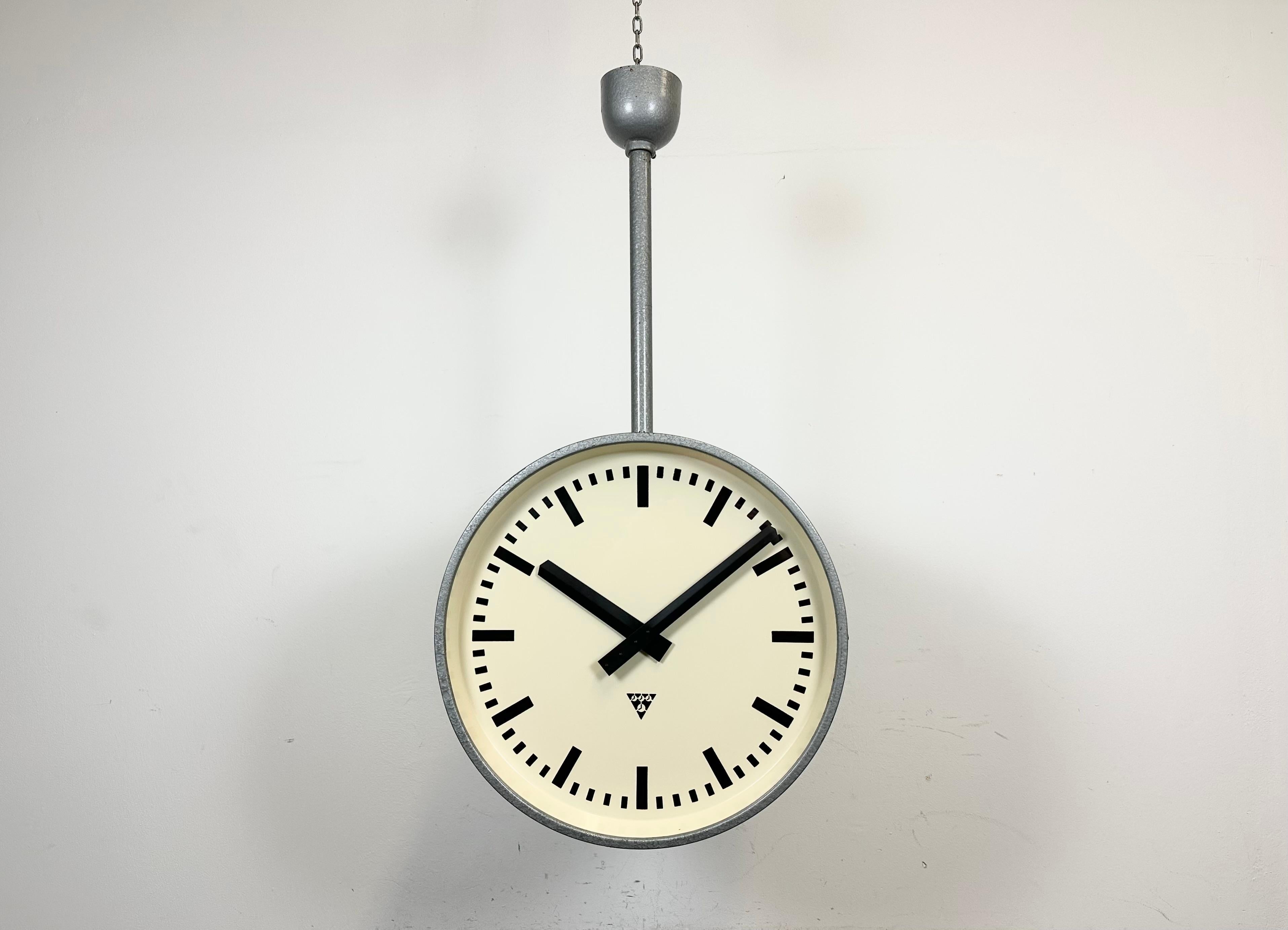 This large double sided railway or factory clock was produced by Pragotron, in former Czechoslovakia, during the 1960s. The piece features a grey Hammer paint metal body and a clear glass cover. The clock has been converted into a battery-powered