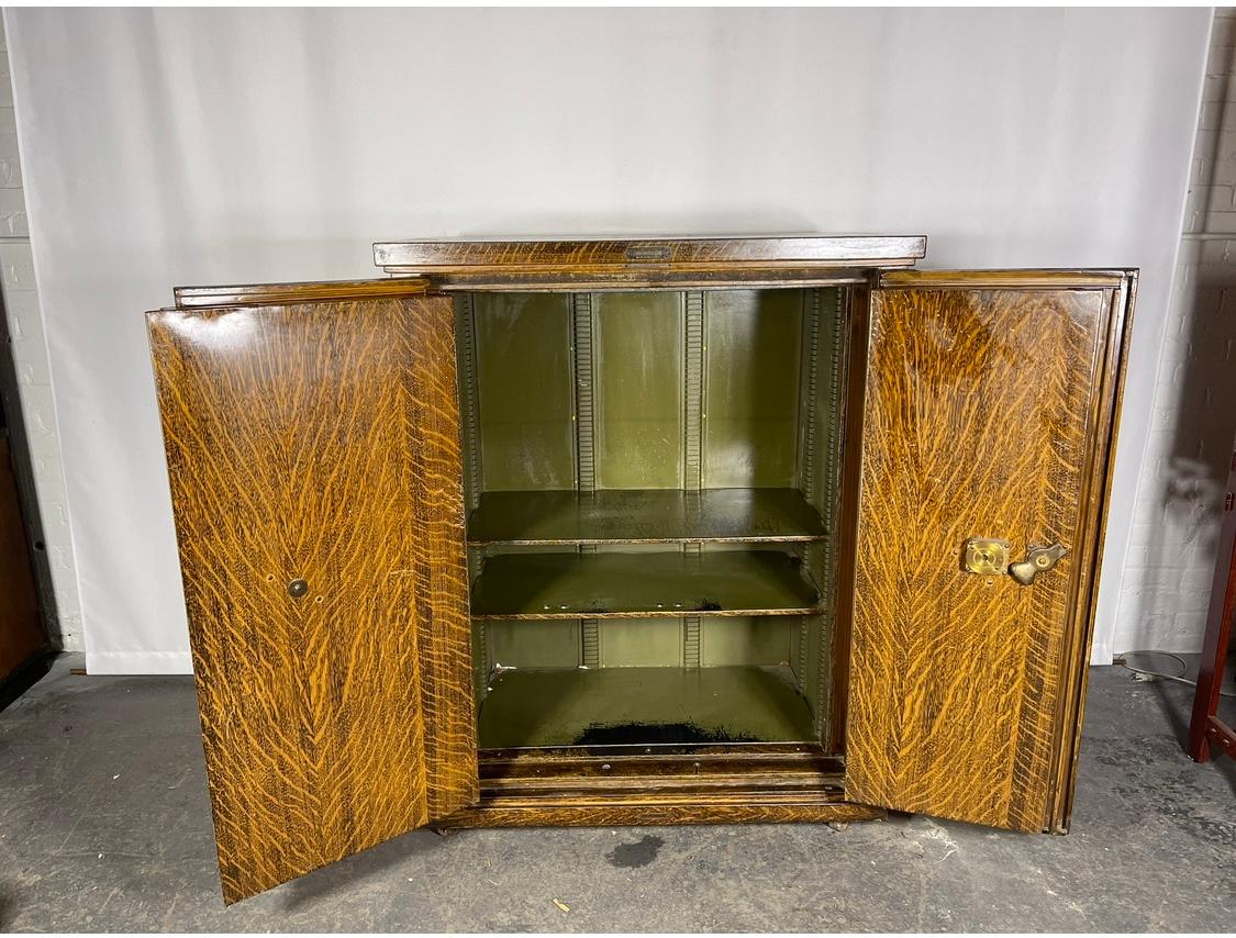 Stately, early 20th century, safe cabinet by The Safe Cabinet Co, Marietta OH features stunning faux wood grain exterior with brass handle and combination lock and original paint interior with adjustable shelves. Hand delivery avail to New York City