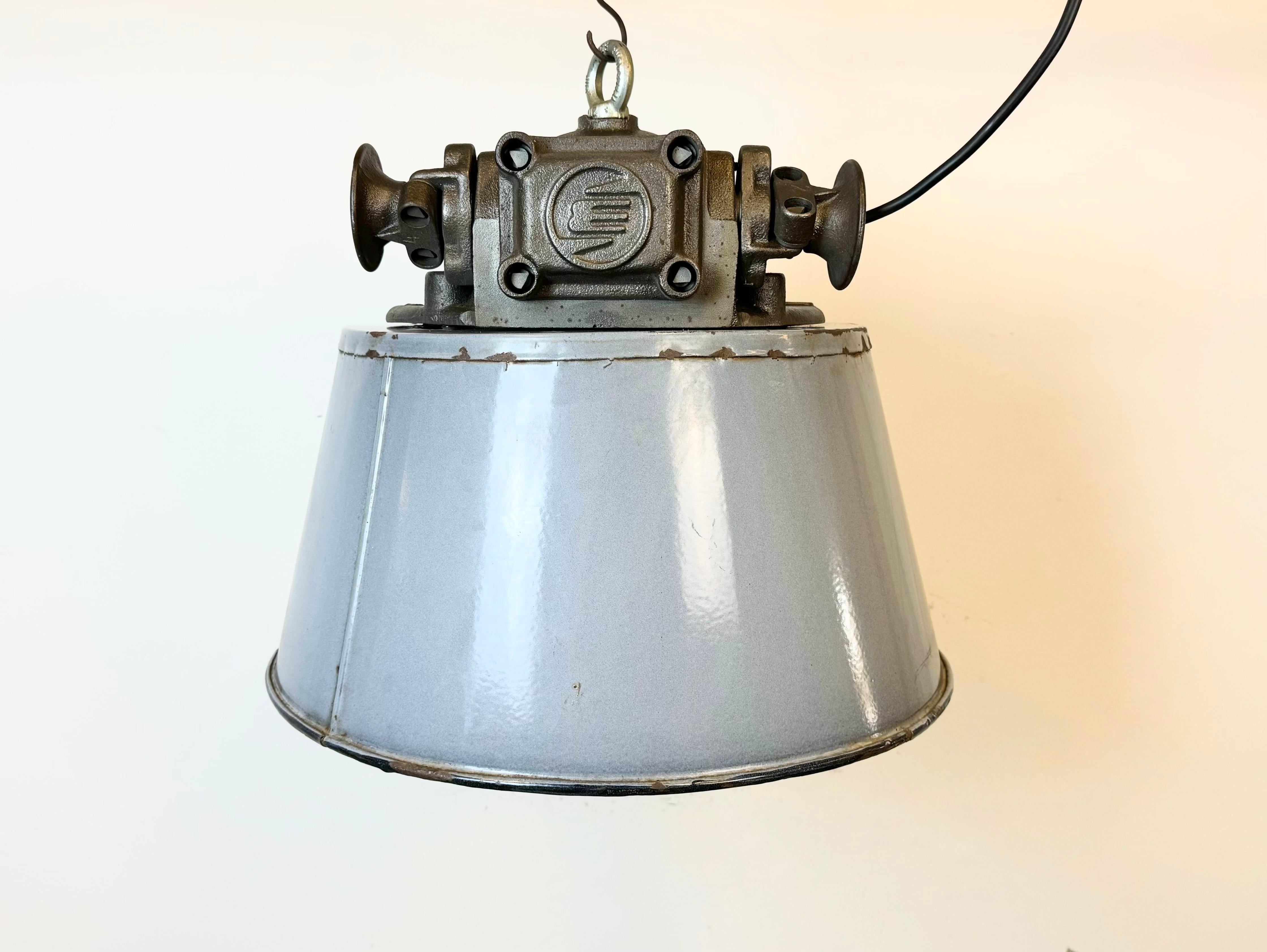 Large heavy industrial hanging lamp made by Elektrosvit in former Czechoslovakia during the 1960s. It features a grey enamel shade with white enamel interior, a cast iron body and a clear glass cover. The porcelain socket requires standard E 27/ E27