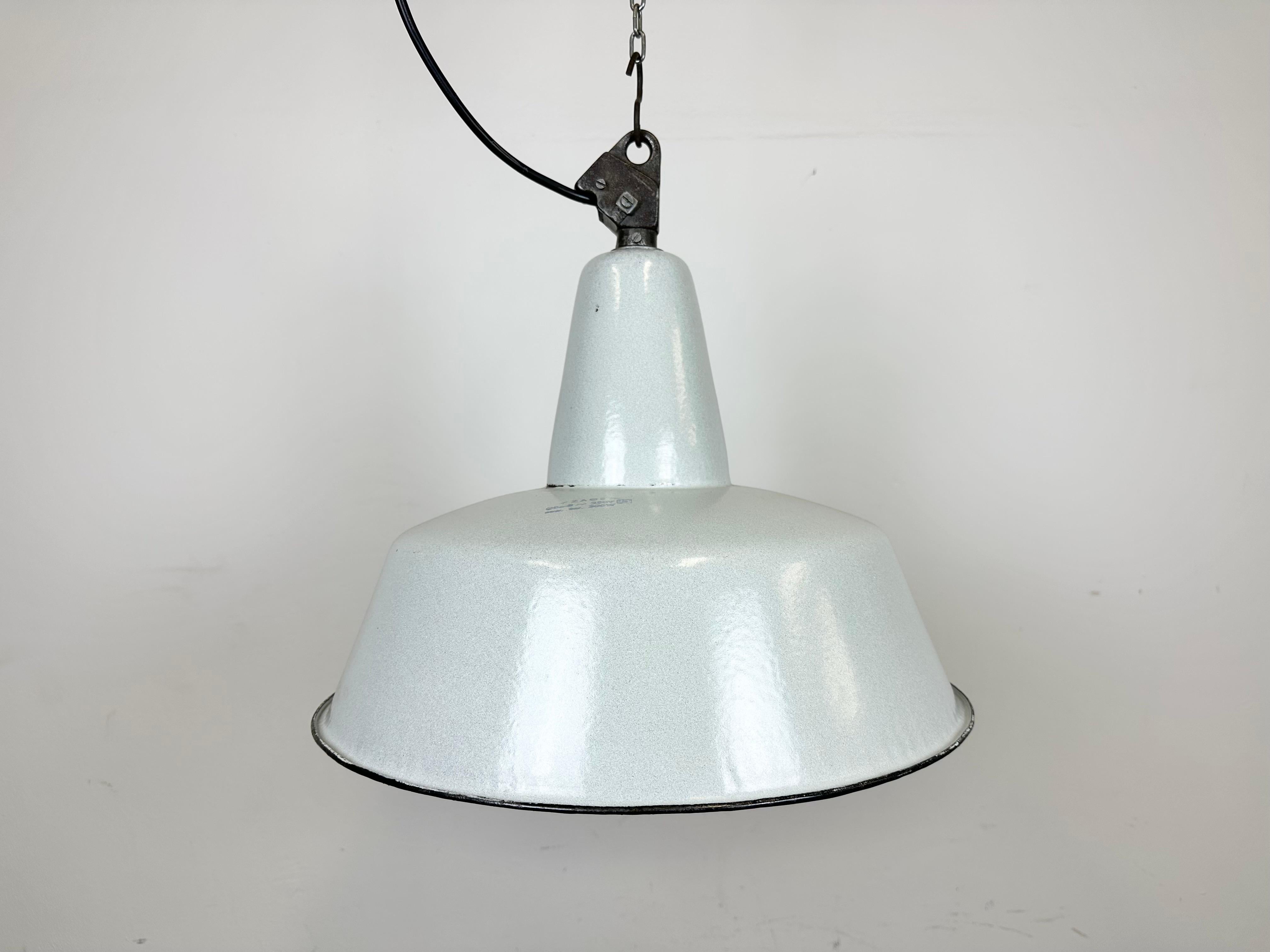 Industrial grey enamel pendant light made by Zaos in Poland during the 1960s. White enamel inside the shade. Cast iron top. The socket requires E 27/ E 26 light bulbs. New wire. The weight of the lamp is 2.3 kg.The diameter of the lamp is 42 cm.