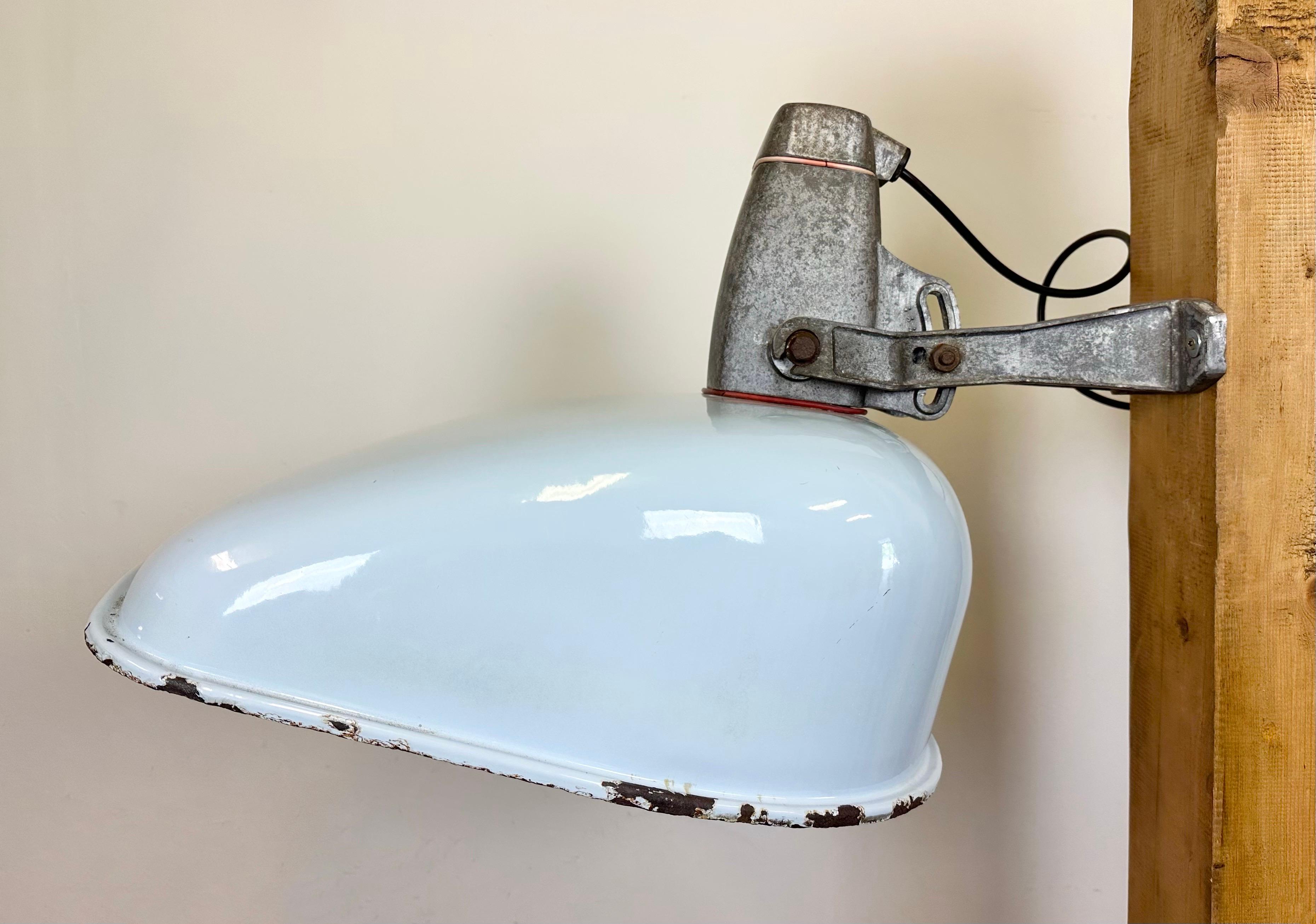 Industrial wall light with adjustable angle made in England during the 1960s. It features a light grey enamel shade with white enamel interior and a cast aluminium wall mounting. The porcelain socket requires E27/E26 light bulbs. New