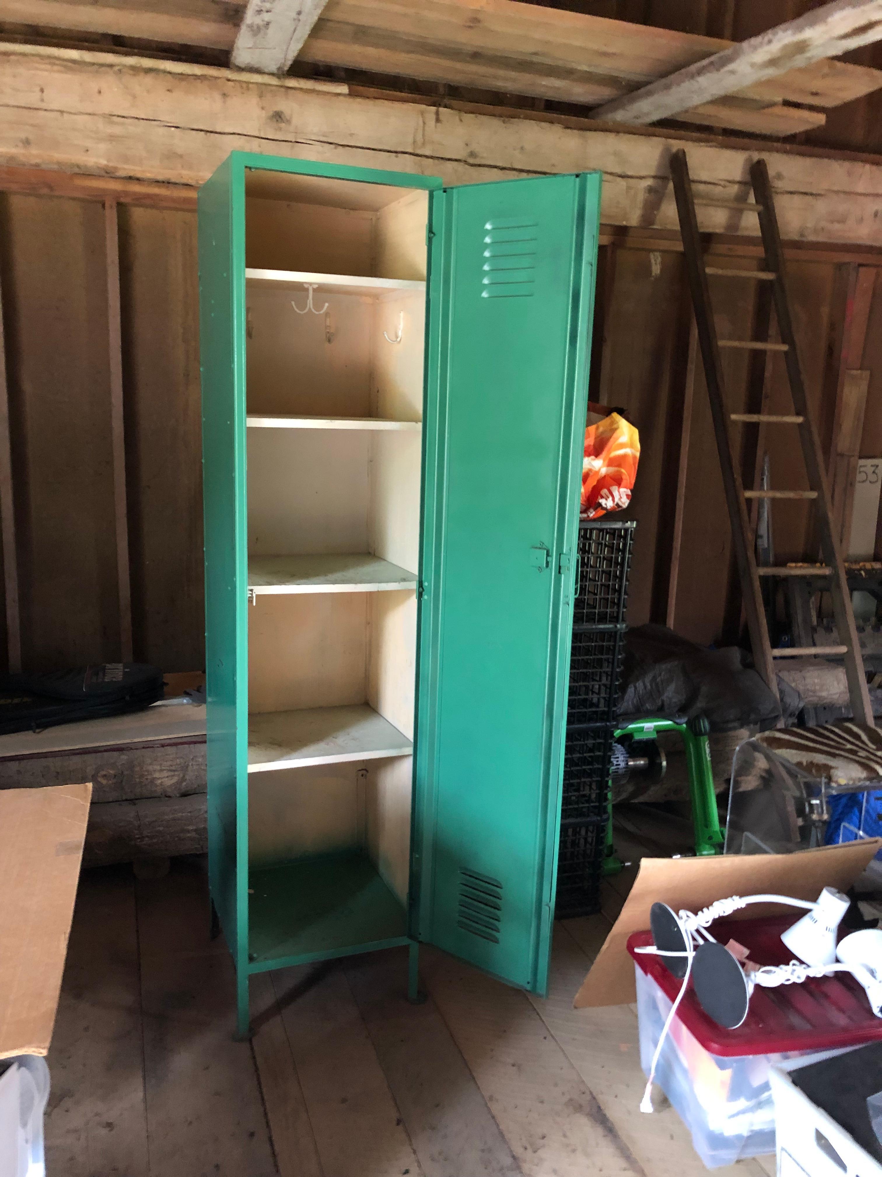 Very tall functional metal industrial locker cabinet in a striking kelly green with cream colored interior.  Multiple shevles and hooks inside.