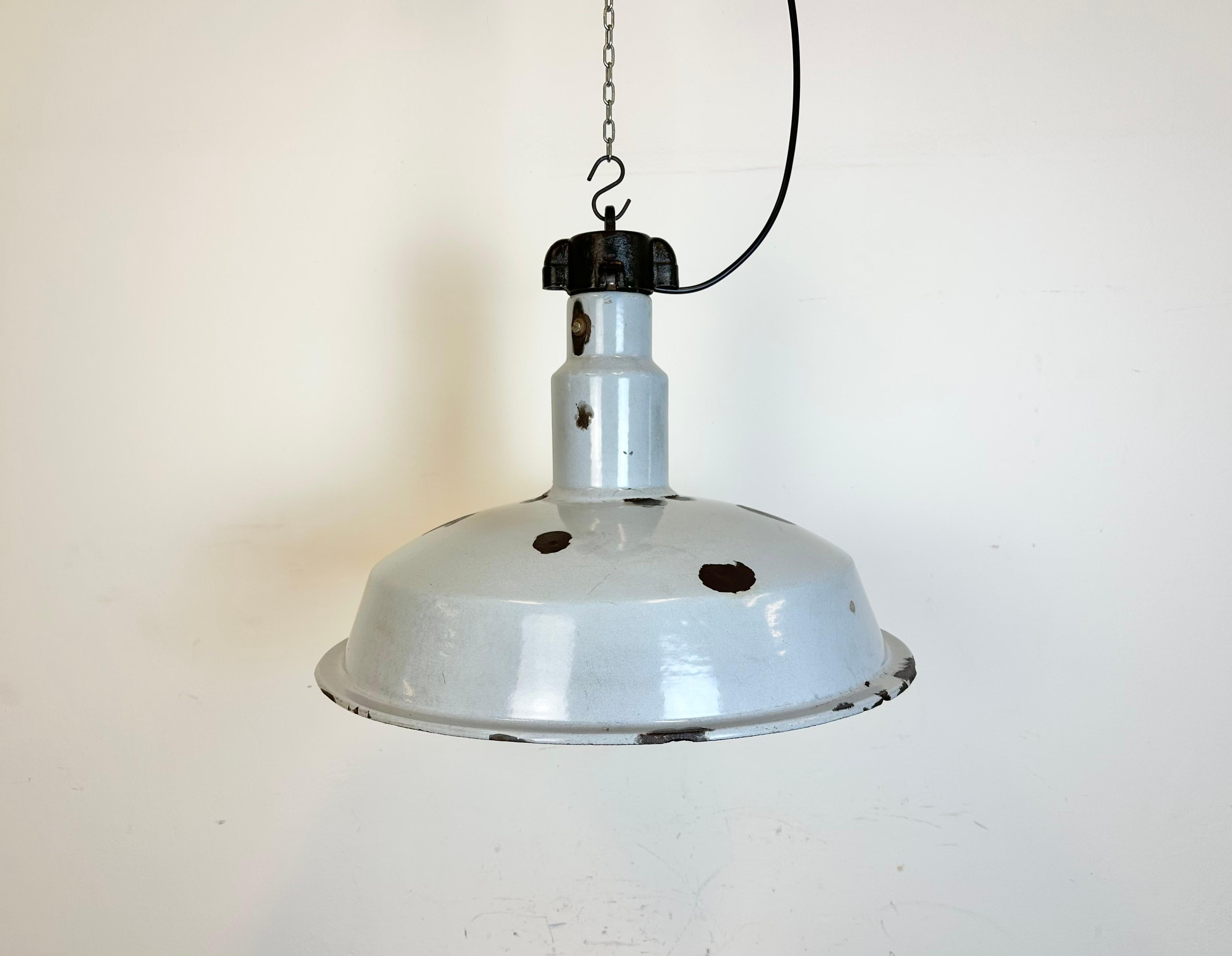 This industrial lamp was made in former Czechoslovakia during the 1950s. It features grey enamel shade with white interior. Cast iron top. New porcelain socket reqiures standard E 27 / E26 lightbulbs. New wire. The diameter of the shade is 55 cm.