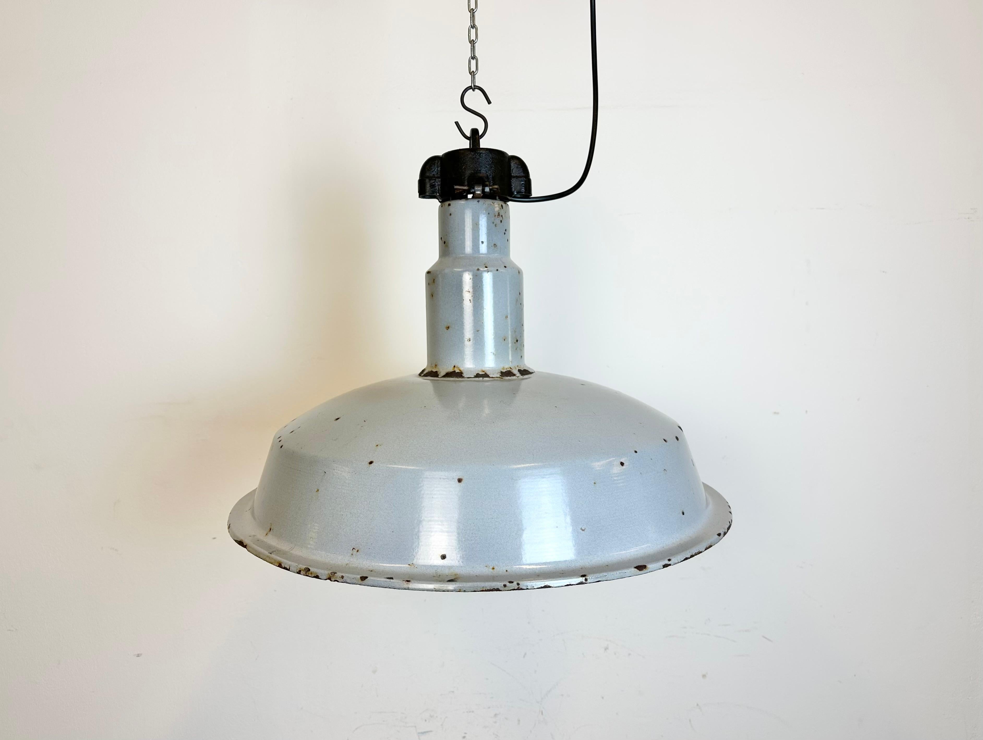 This industrial lamp was made in former Czechoslovakia during the 1950s. It features grey enamel shade with white interior. Cast iron top. New porcelain socket reqiures standard E 27 / E26 lightbulbs. New wire. The diameter of the shade is 55 cm.