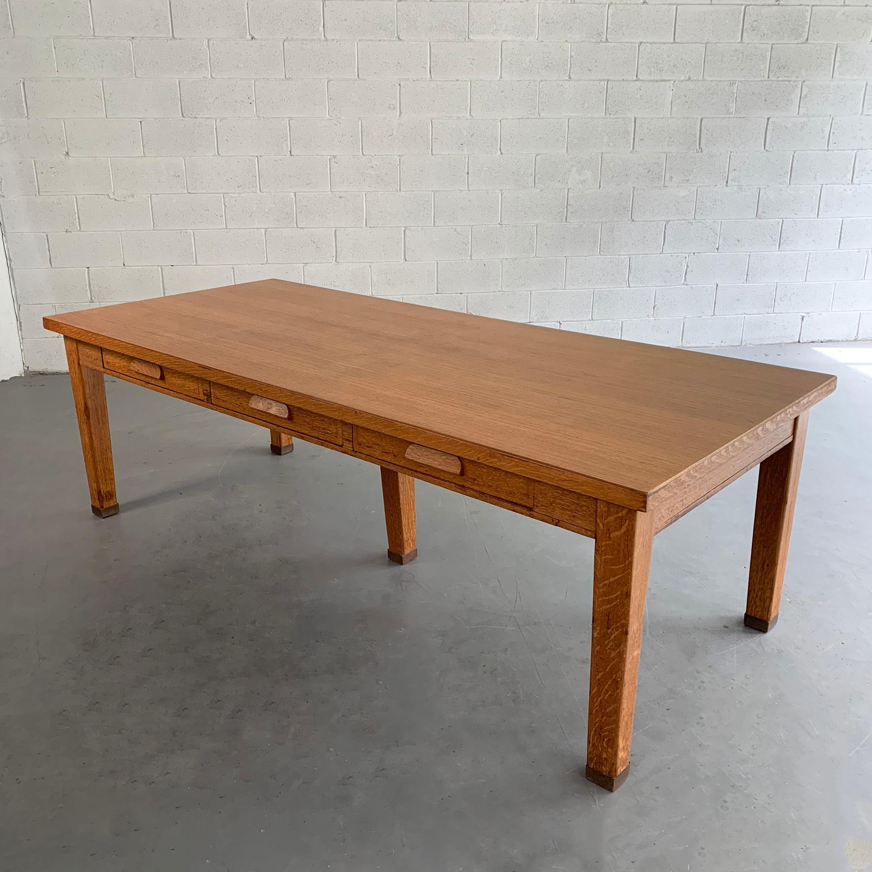 Large, 8 ft, industrial, oak library table features 3 drawers on each side with brass capped legs. The table is versatile and can be used as a dining table, partners desk or large work table. The leg height clearance is 24.5 inches.