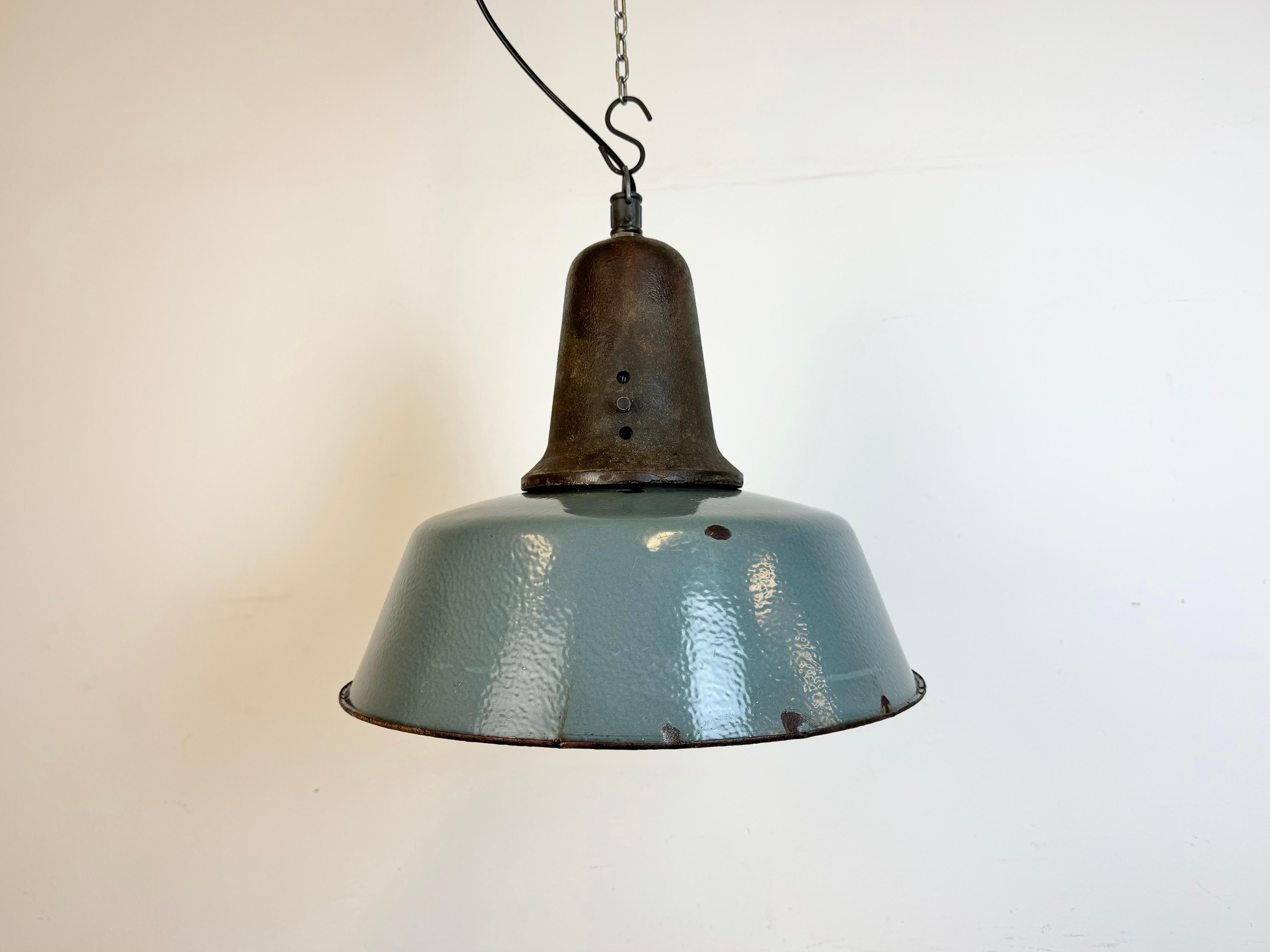 Industrial grey enamel pendant light made in Poland during the 1960s. White enamel inside the shade. Cast iron top. The porcelain socket requires standard E 27/ E26 light bulbs. New wire. Fully functional. The weight of the lamp is 4,5 kg.