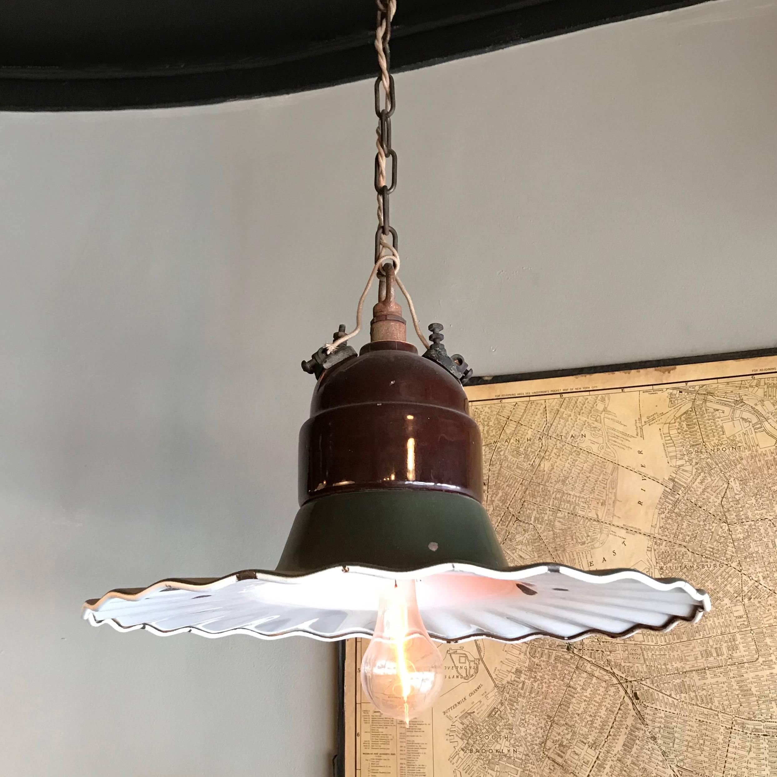 Large, industrial, gas station pendant light features a pie crust ruffle, green and white porcelain enameled shade with brown enameled fitter on 36 inches of chain. The lamp is newly wired to accept up to a 200 watt bulb. The hanging length is