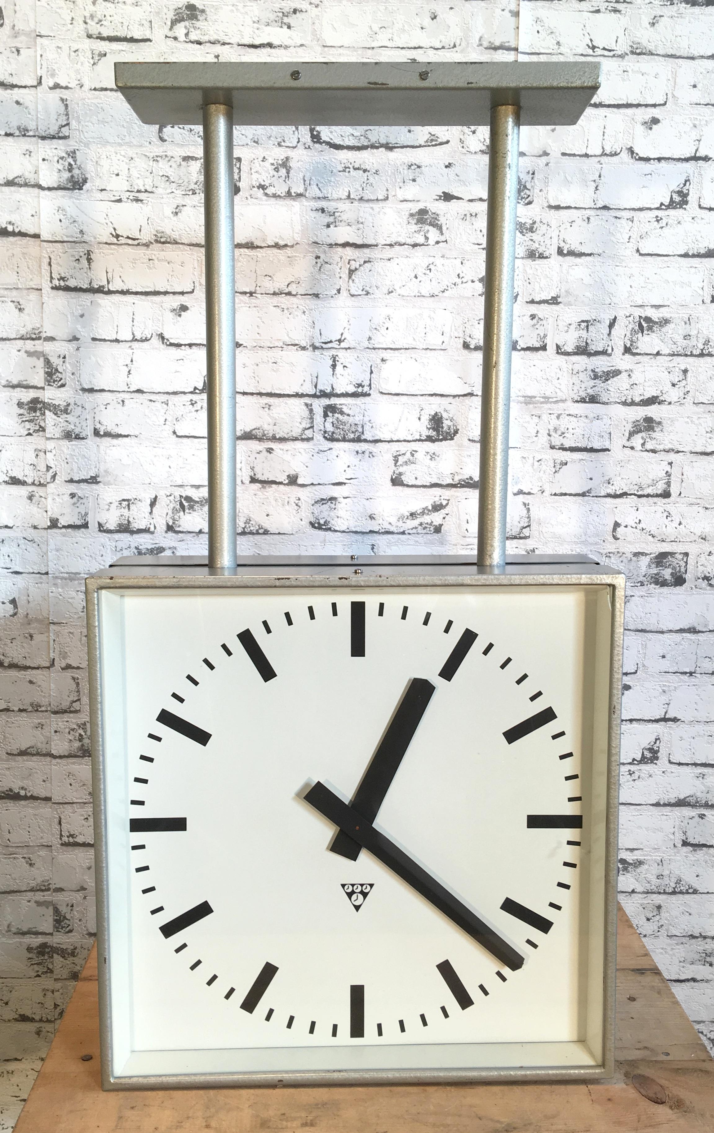 This square double sided railway, school or factory clock was produced by Pragotron, in former Czechoslovakia, during the 1960s. The piece features a grey metal body, clear glass cover ,aluminum dial and hands. The clock has been converted into a