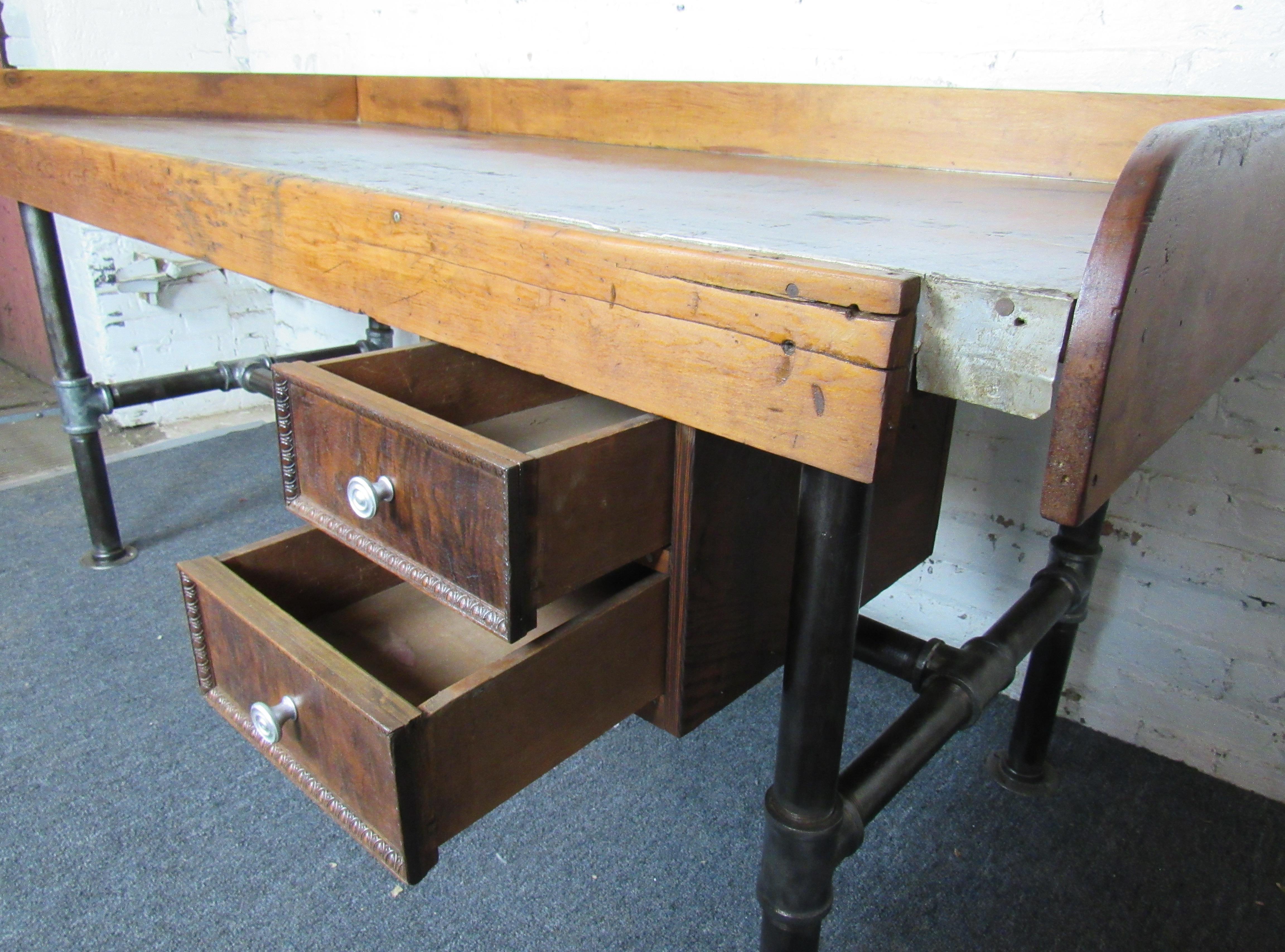 Esta mesa de trabajo grande y robusta está llena de encanto desgastado y detalles de mediados de siglo. Los bordes elevados evitan que los objetos se caigan o rueden por la superficie, y los cajones adicionales añaden funcionalidad.