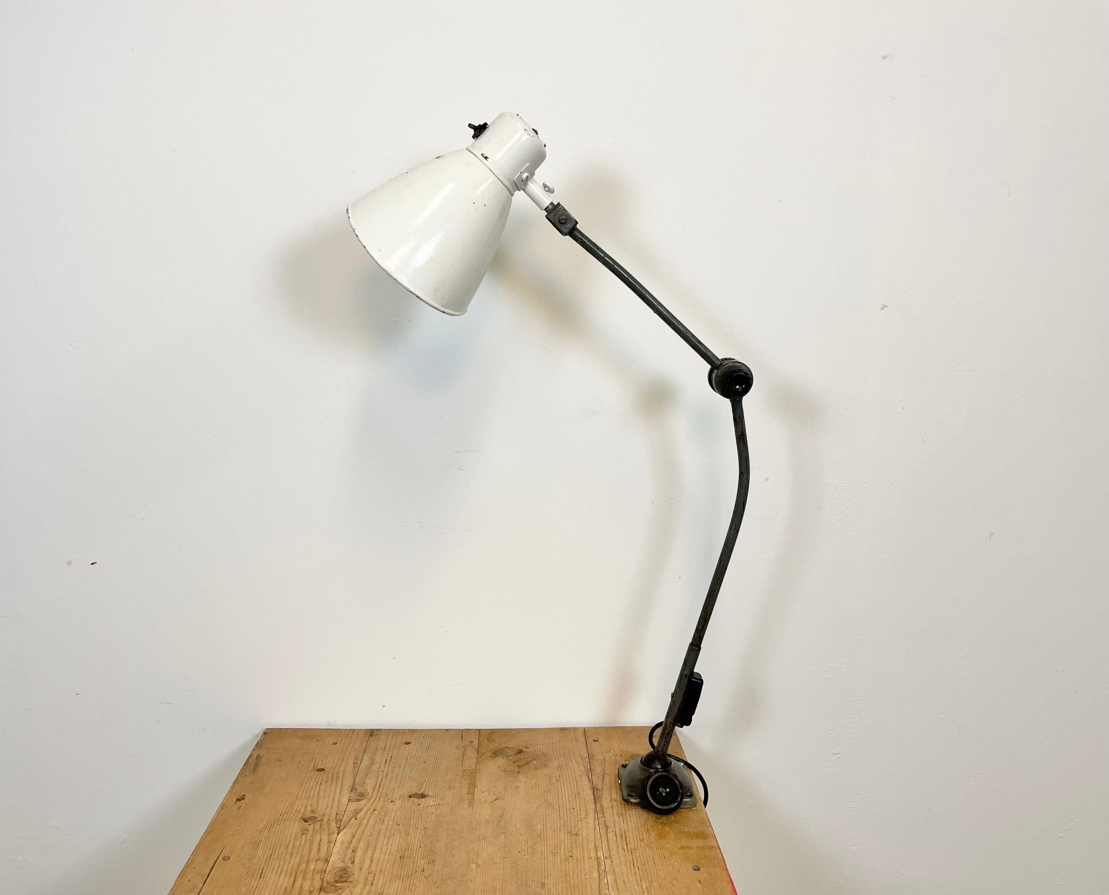 Large industrial table lamp with three adjustable joints made in former Czechoslovalia during the 1960s.It features grey iron base and arm and white lampshade with original switch. The porcelain socket requires E 27/E 26 light bulbs. New wire. The