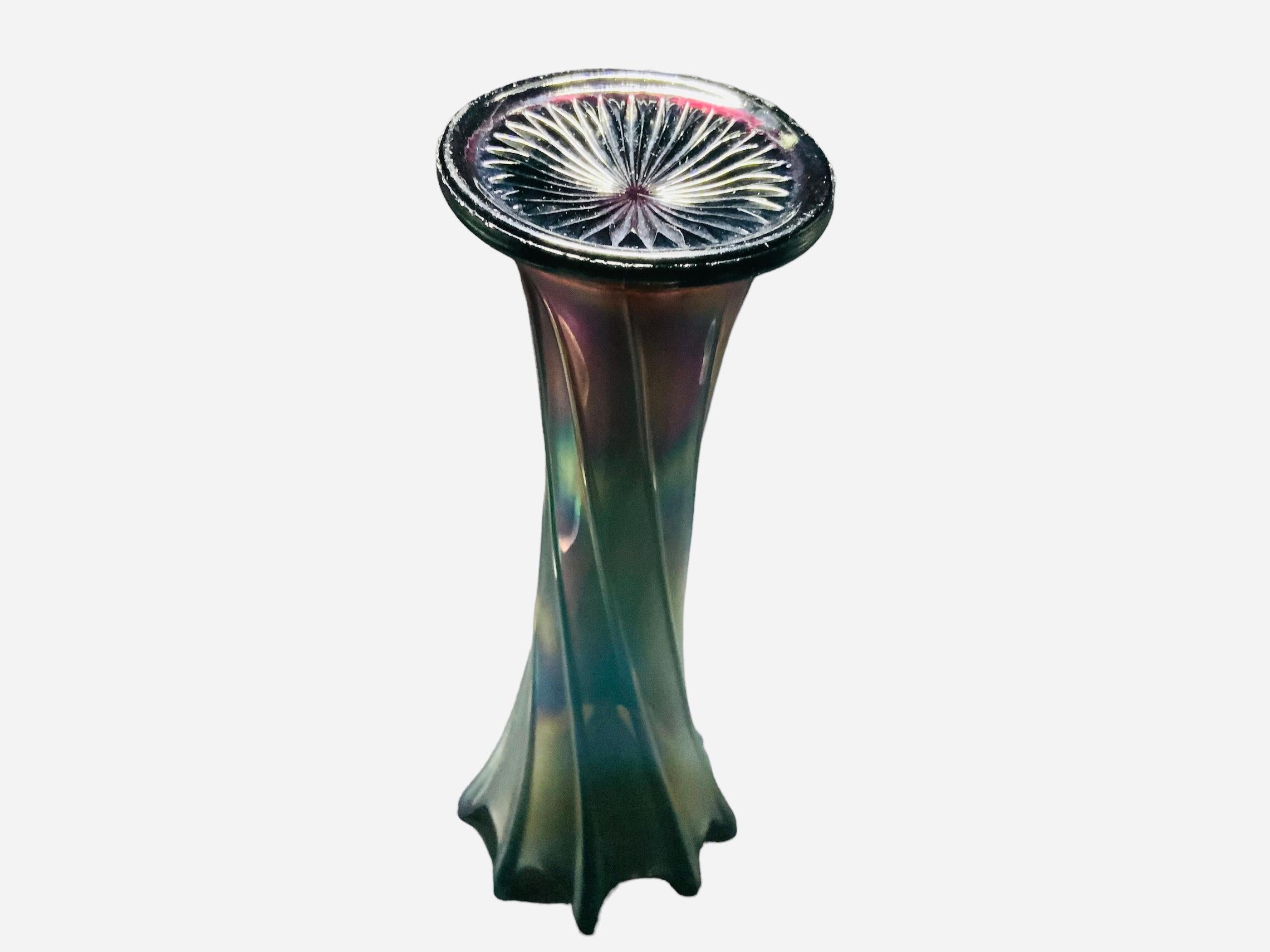 This is a large iridescent glass flower vase. It depicts a multicolored glass flower vase with high waves upper border. The whole vase is adorned with reeded bands that match the tips of the waves.