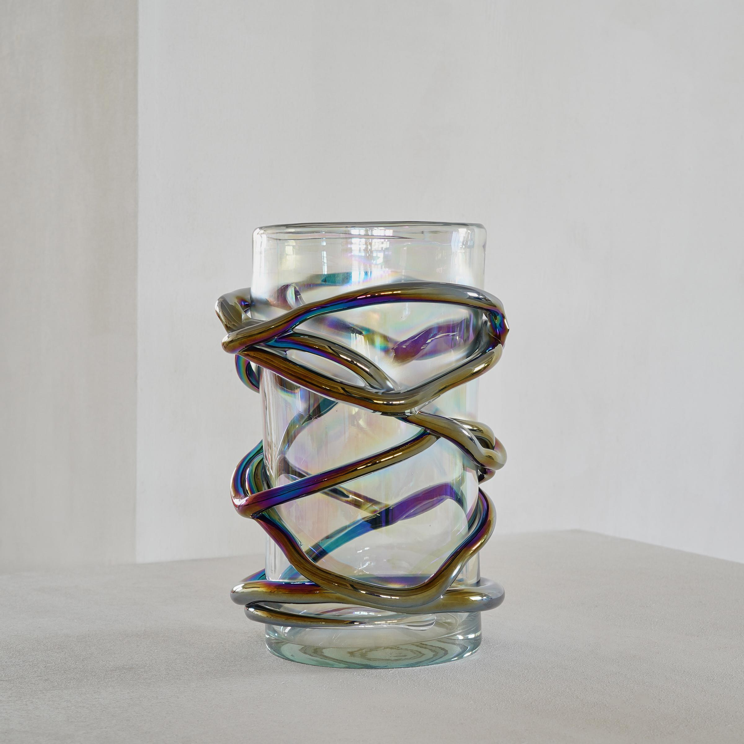 This is a very unique and playfully designed glass vase made by a skilled Murano glass workshop in Venice Italy.
 
There is a fantastic iridescent finish on the glass strokes that are playfully embracing the clear glass. The result is a real