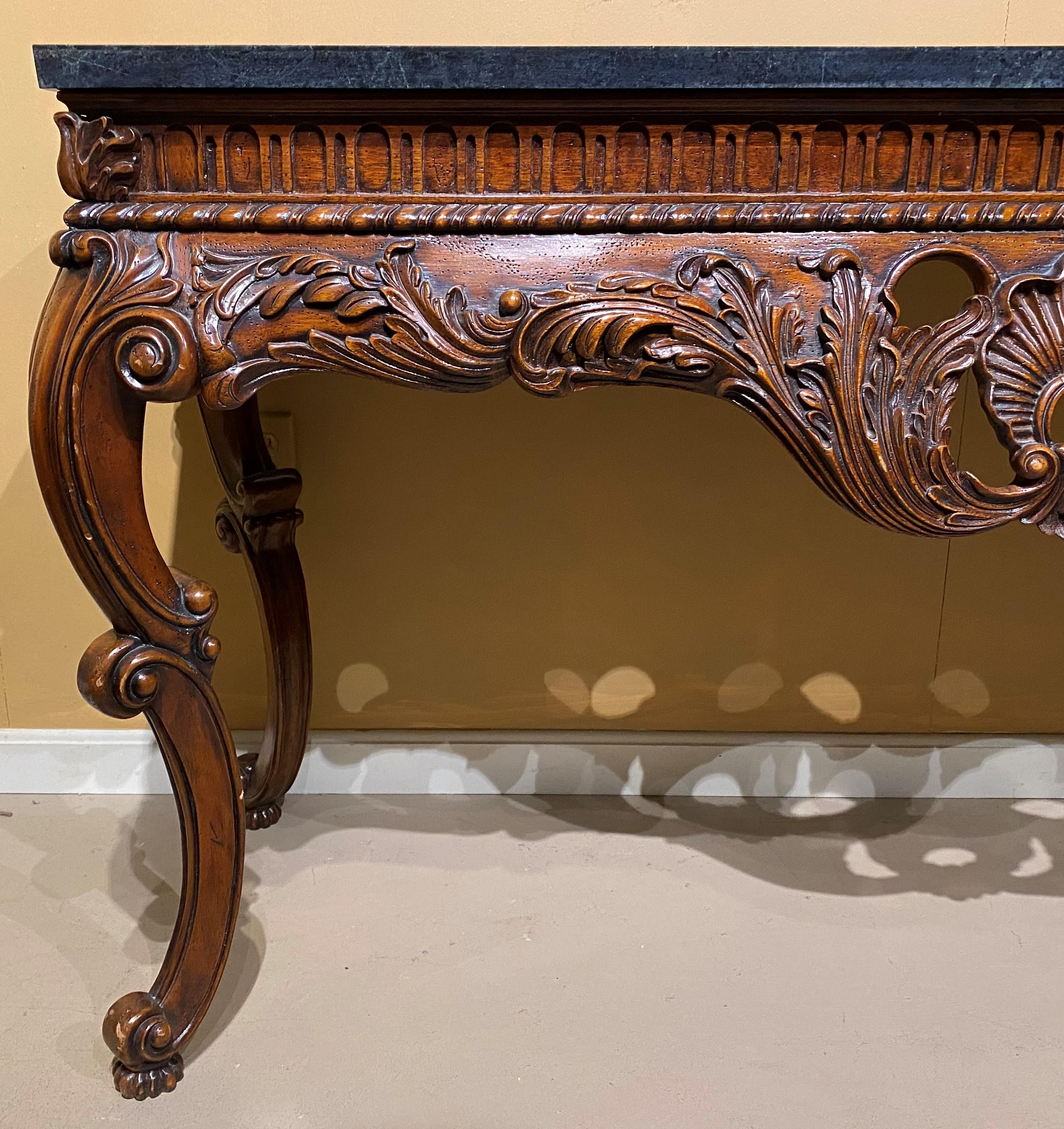 A large Irish Rococo style scroll carved fruitwood console with green faux stone rectangular top surmounting and impressive foliate carved frieze with reticulated center shell drop, supported by four cabriole scrolled legs terminating with scroll