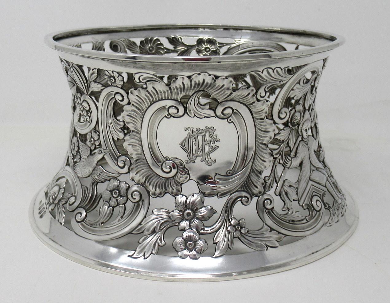 An exquisite Irish Georgian style Dublin silver heavy gauge table dish ring of traditional waisted form and unusually large size.

The circular inverted sided lavish pierced body depicting birds in flight, a shepherd, fisherman and a peasant in