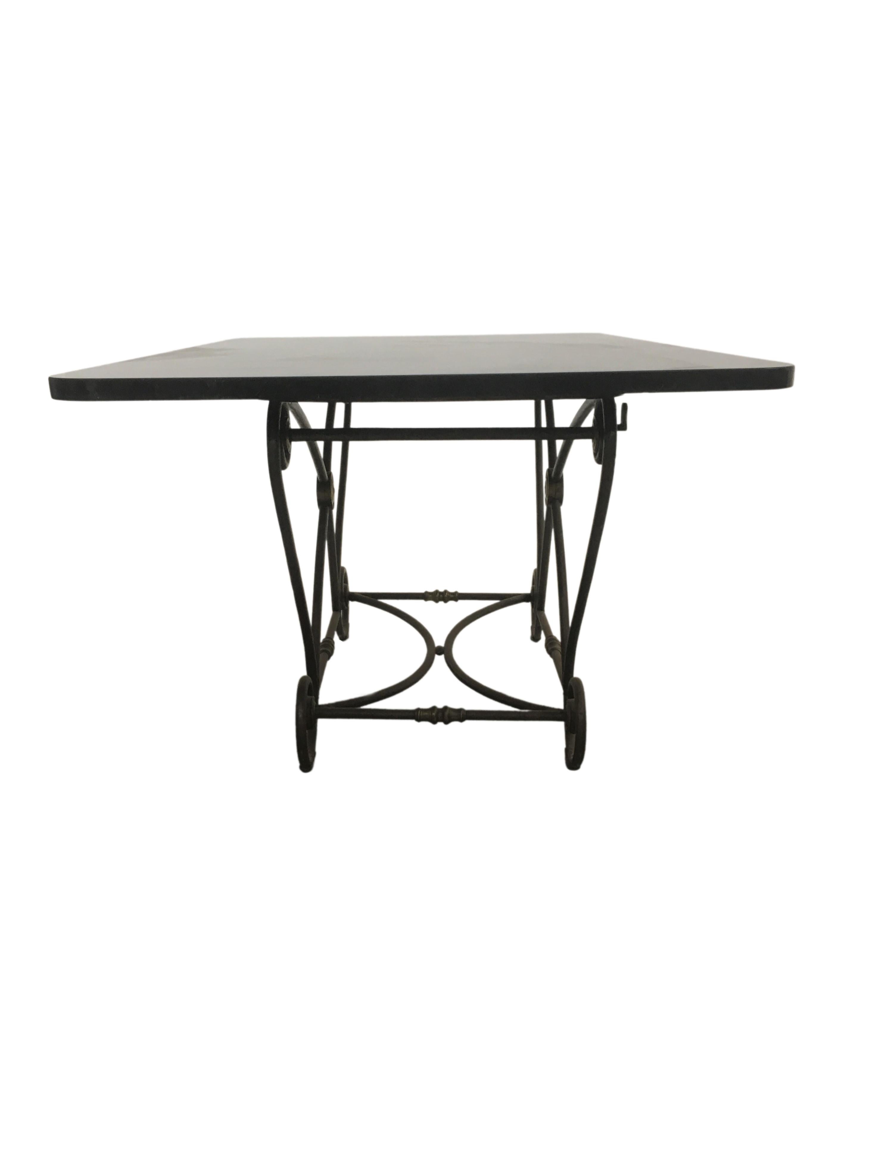 A 1920s dining, or kitchen work table. An iron base with brass decoration medallions finished with a heavy black marble top.