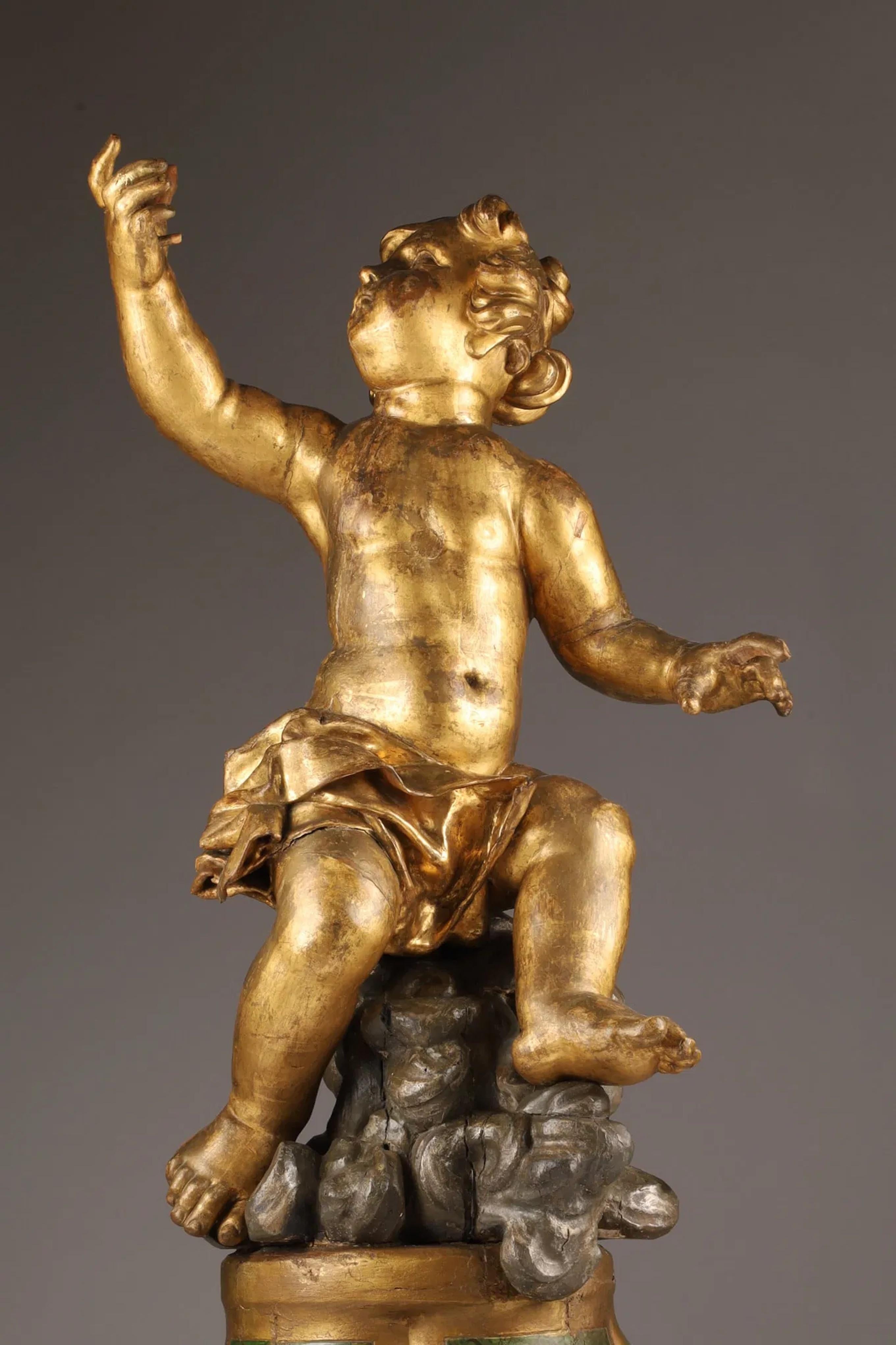 Large Italian 18th C Carved Giltwood Figure of a Putto Gesturing Seated upon a polychrome Trompe L'Oeil painted pedestal base. Italy: Second half of 18th Century