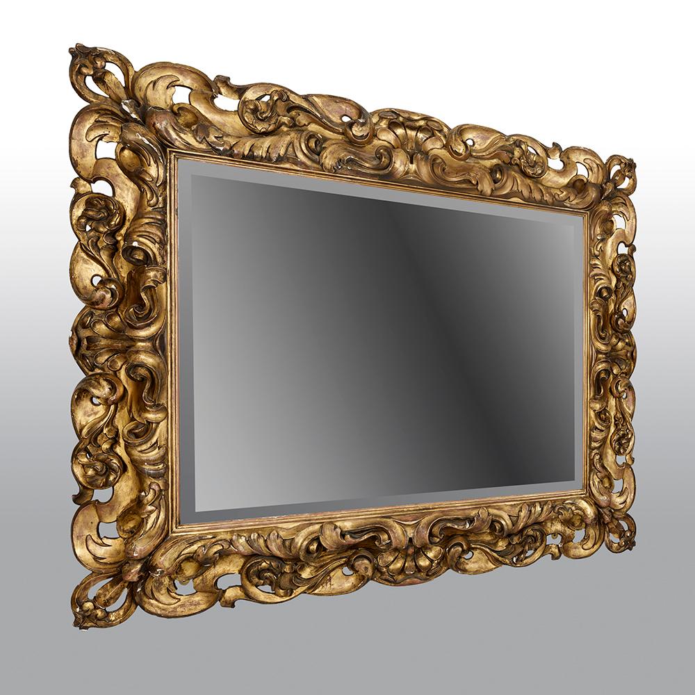 Dieser großformatige italienische Spiegel aus geschnitztem Goldholz aus der zweiten Hälfte des 19. Jahrhunderts hat einen reich geschnitzten rechteckigen Rahmen aus Goldholz, der typisch für die Rokokozeit ist.