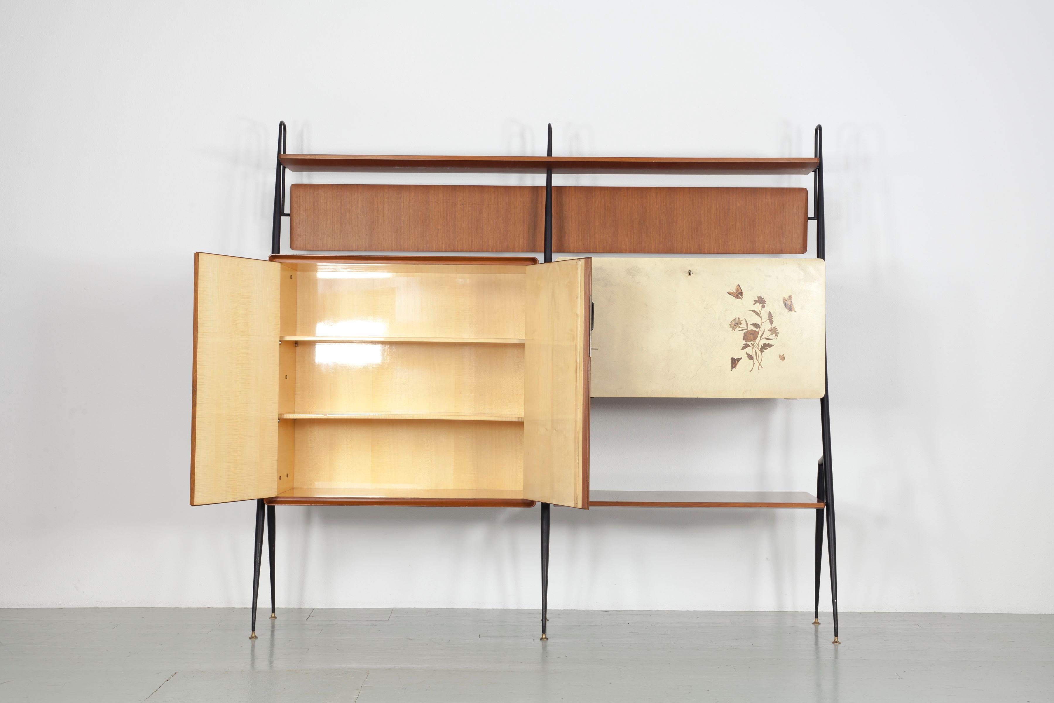 Large Italian 1950s wall unit by Silvio Cavatorta. 
The teakwood elements with black lacquered metal supports on the sides and height-adjustable brass feet offer a lot of storage space.
The bar element has a hinged parchment covered door with
