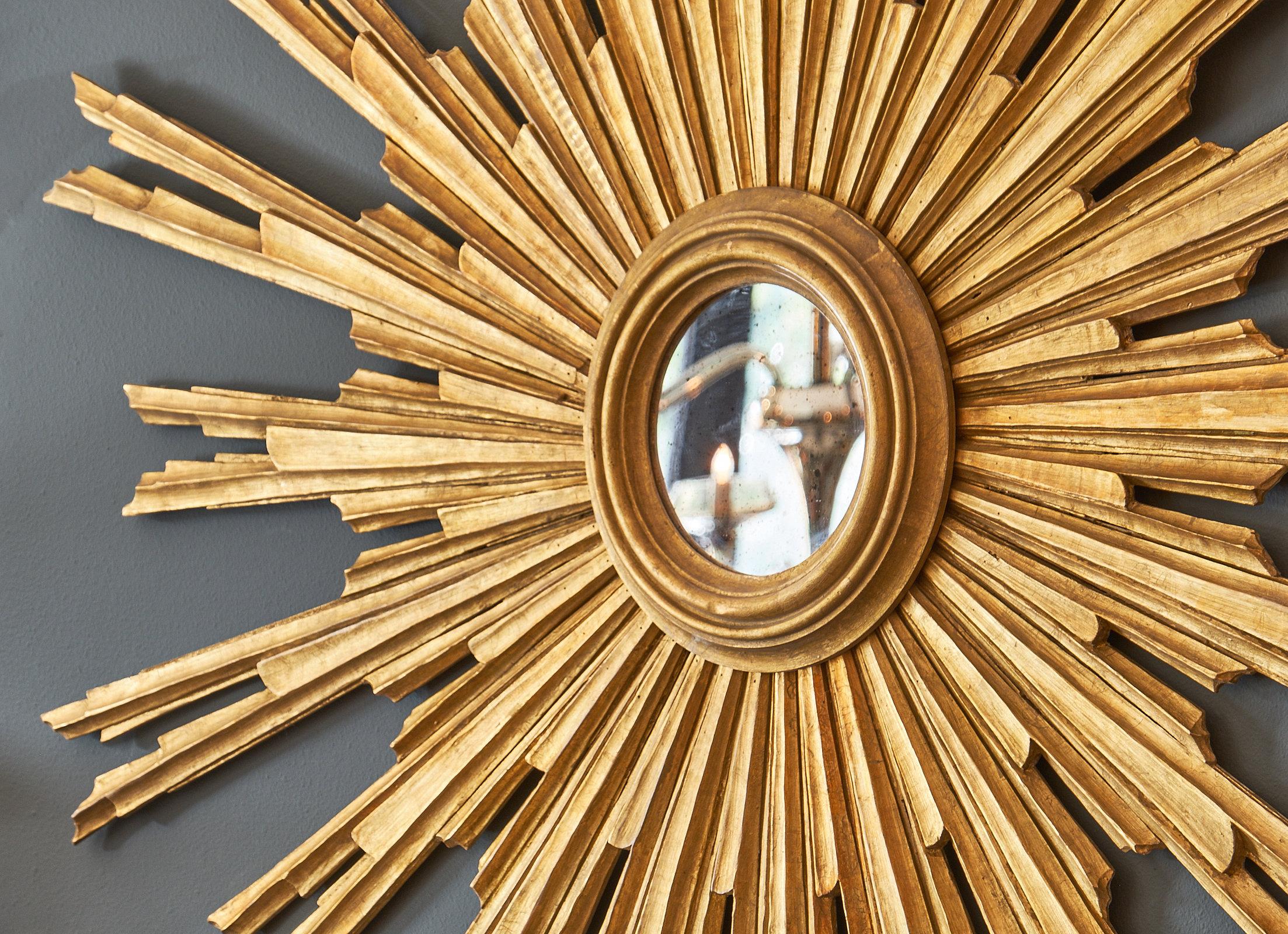 An Italian Renaissance style sunburst mirror featuring multiple hand carved and gold leafed rays and a central round mirror from Florence, Italy.