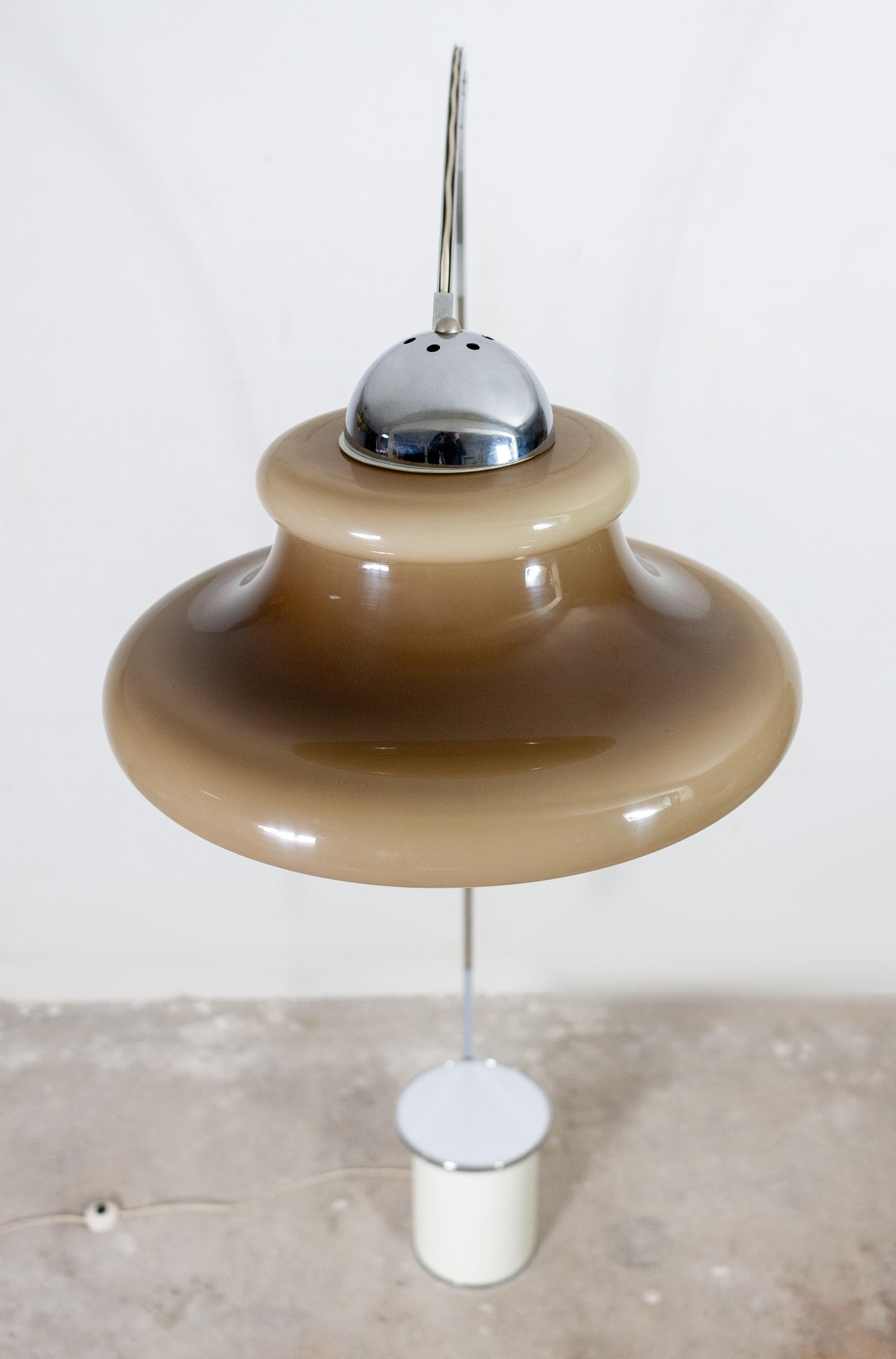 Large Italian arc lamp. Very high 240cm. So you can walk under it. No ugly wire ring
neatly put away in the rail. The counter weight is also a little table. The perspex shade is light
to dark brown, good condition, 1970s.
 