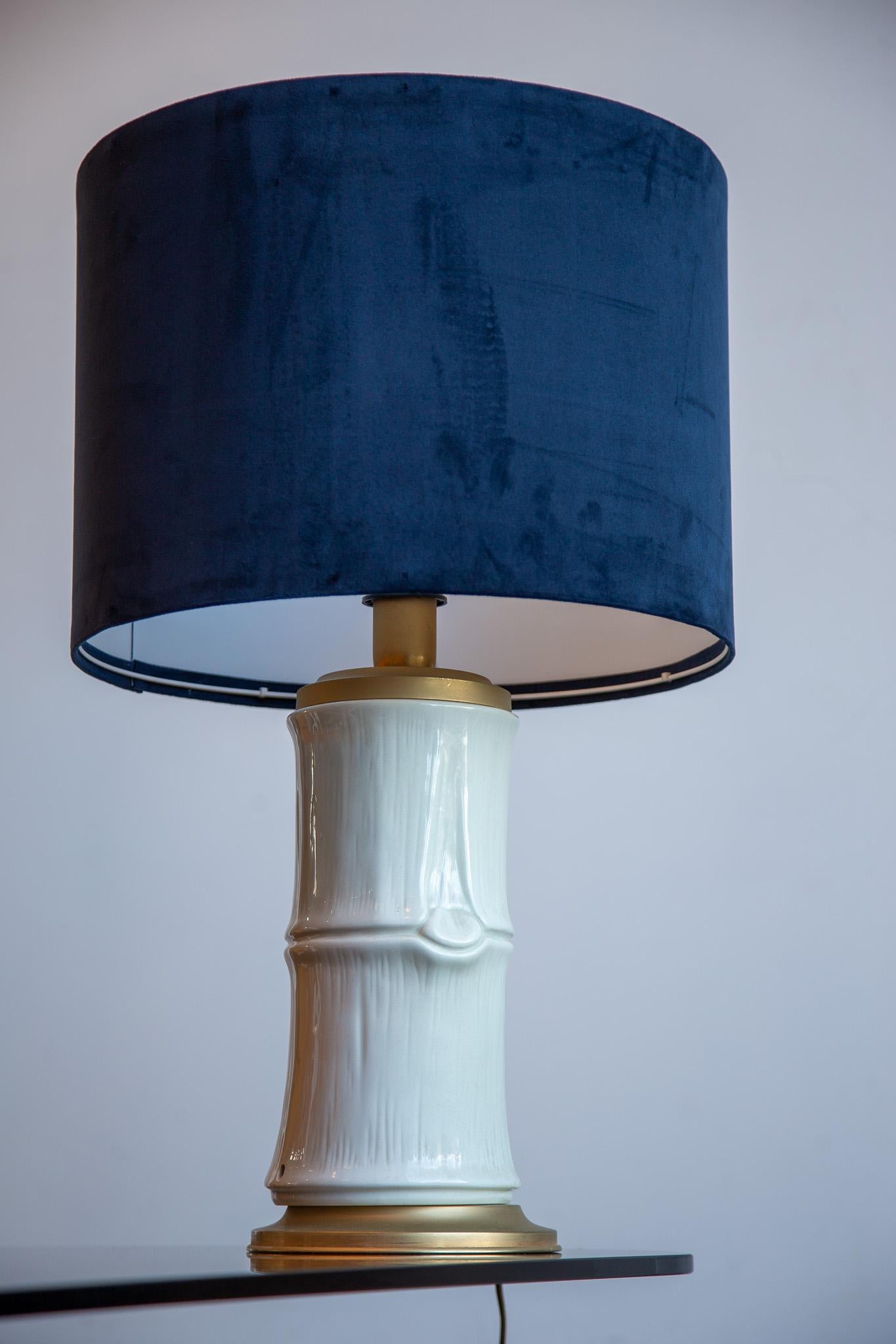 Elegant and sculptural, this vintage Italian table lamp draws inspiration from the organic form of bamboo, rendered in glossy white ceramic with meticulously hand-sculpted grooves and nodules that echo the rhythm of natural cane. The lamp rests on a