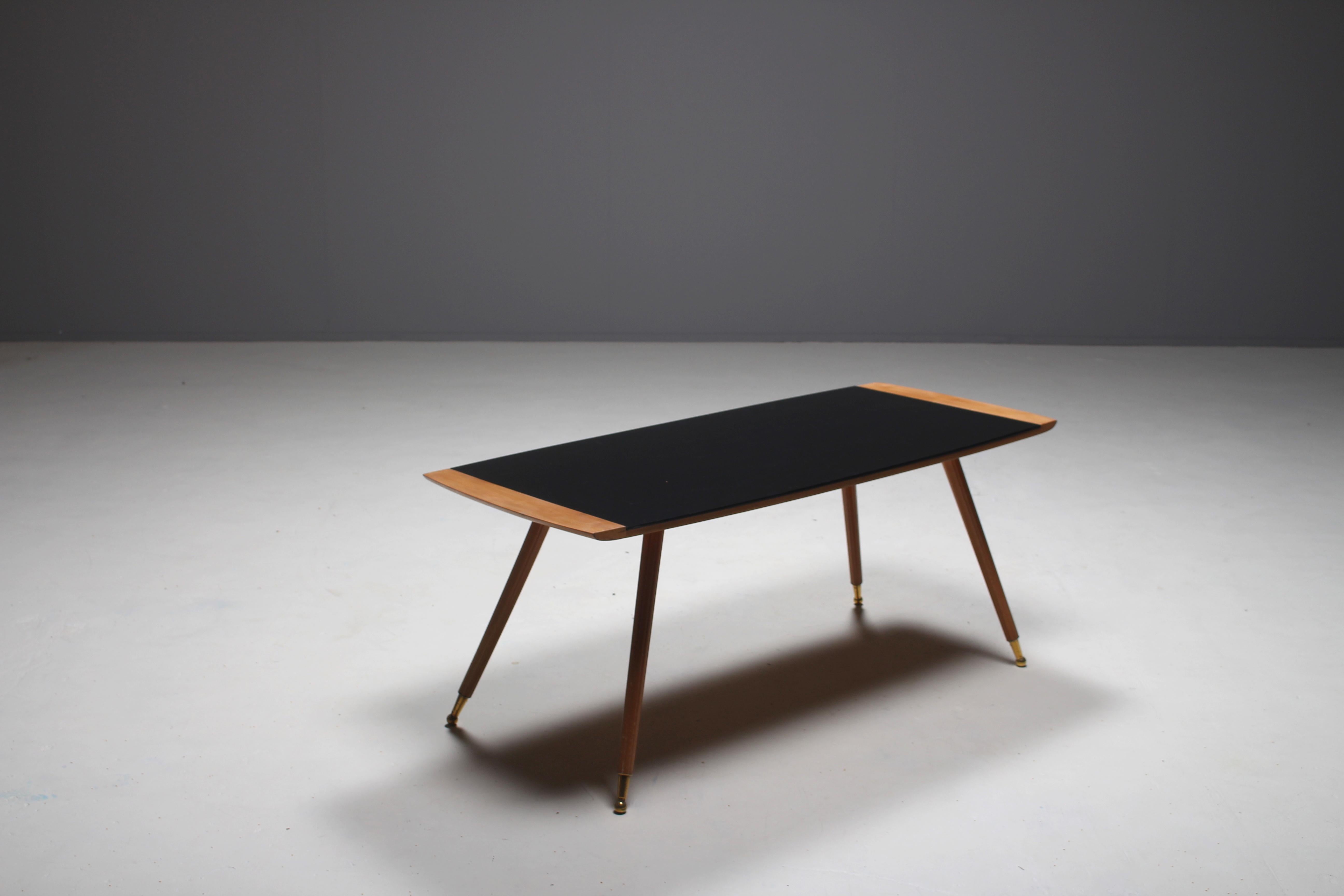 Large Italian coffee table in the manner of Paolo Buffa and Gio Ponti.
The table is made out of beechwood and has brass feet.
Black glass is on top of the table and makes a nice contrast with the light wood and brass feet.
  