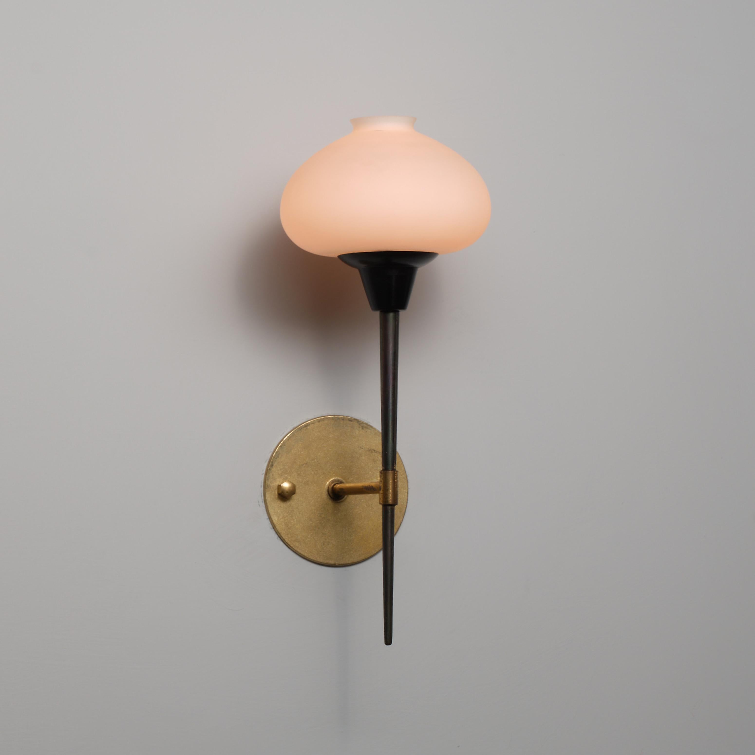 Diseñada y fabricada en Italia en la década de 1950, esta gran lámpara de pared combina una placa circular de latón de 10 cm de diámetro, un esbelto pie patinado oscuro, una carcasa de metal lacado en negro y una pantalla de vidrio opalino soplado a