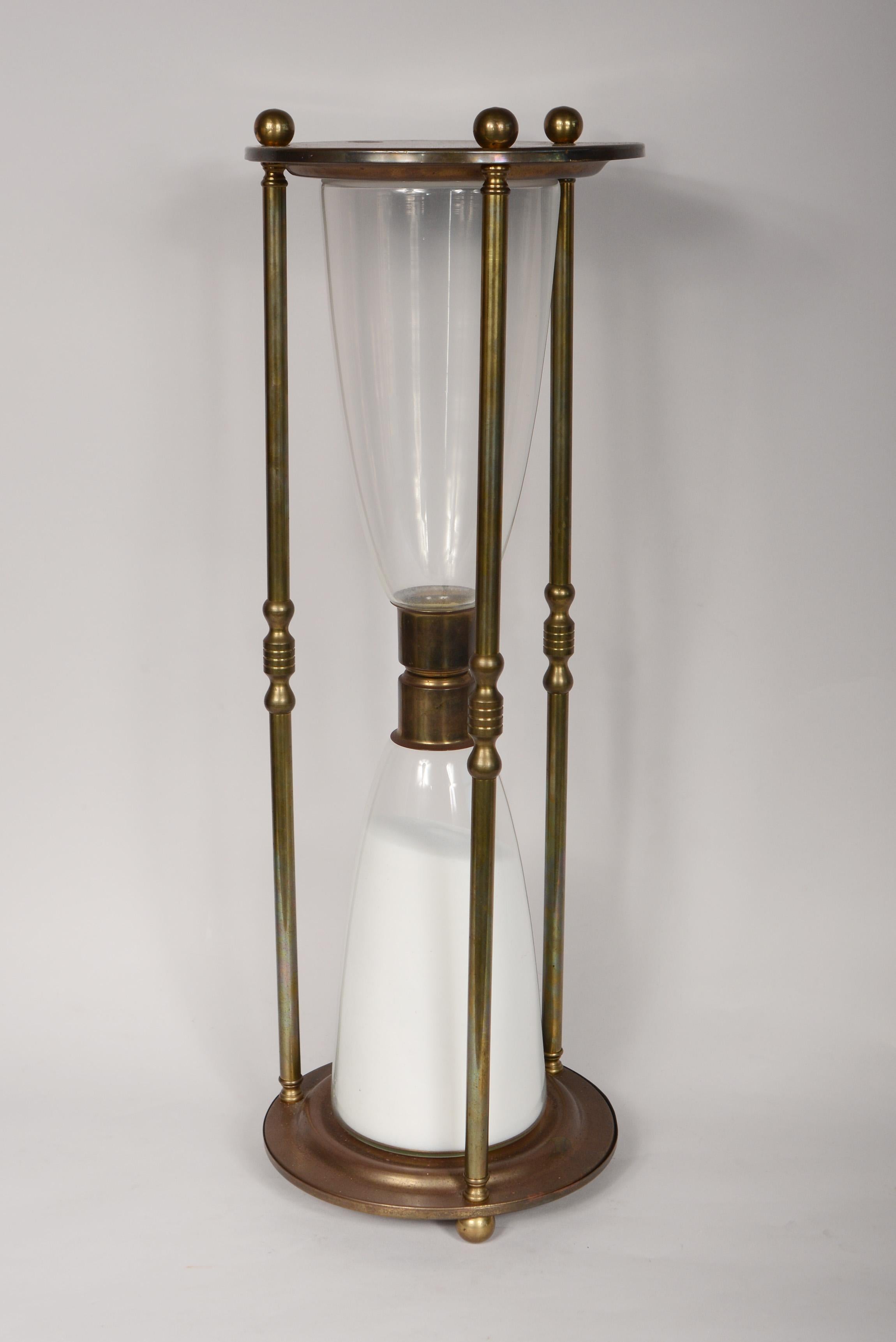 Oversized brass hourglass with ball feet. Pass the time watching the sand fill the bottom of this few hours glass.