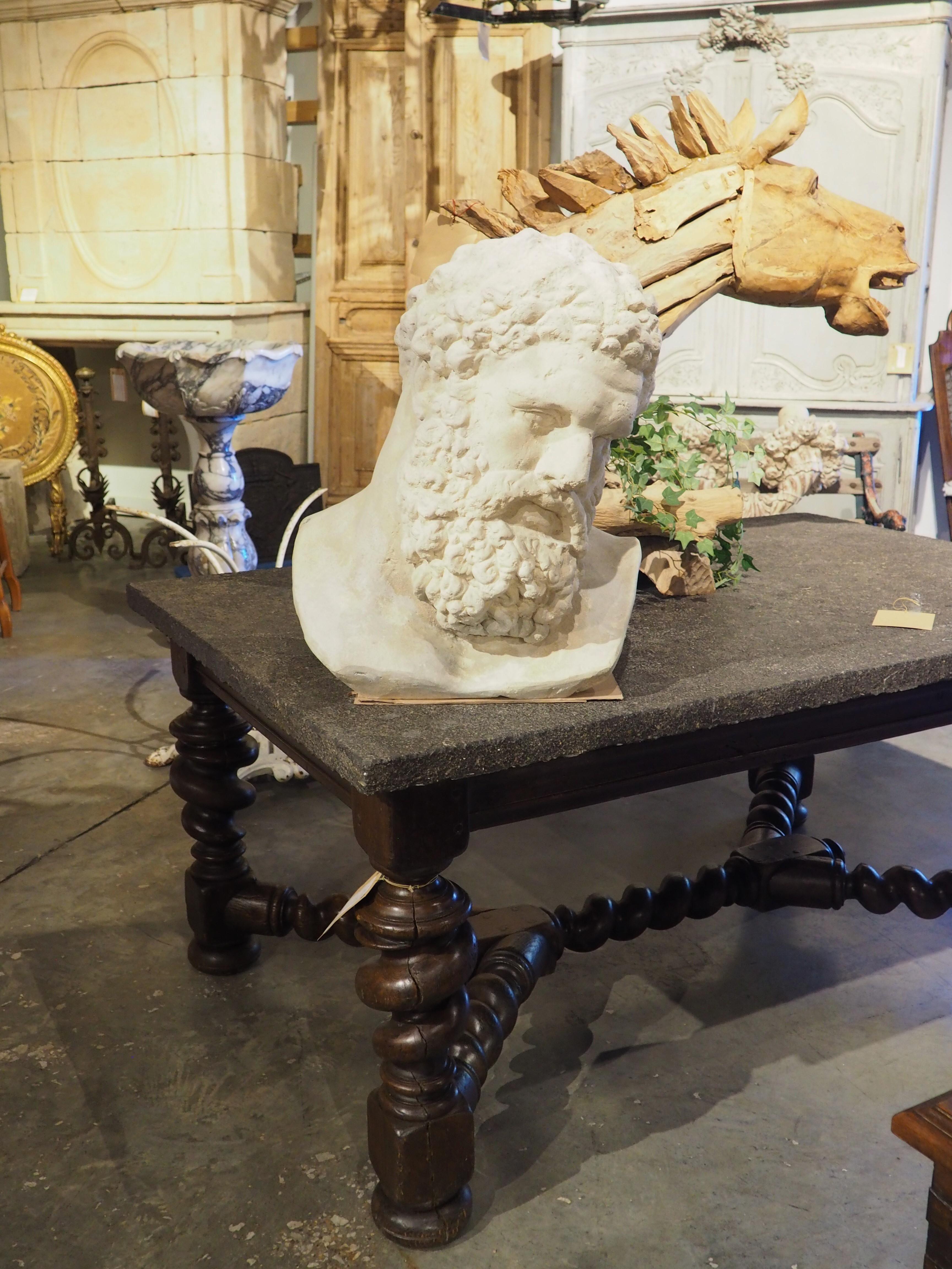 Based after an early 3rd century Farnese statue, this large cast limestone bust depicts the head of Hercules as it appeared in antiquity. His head is tilted to the side and down, while the neck muscles show perfect placement and proportion to the
