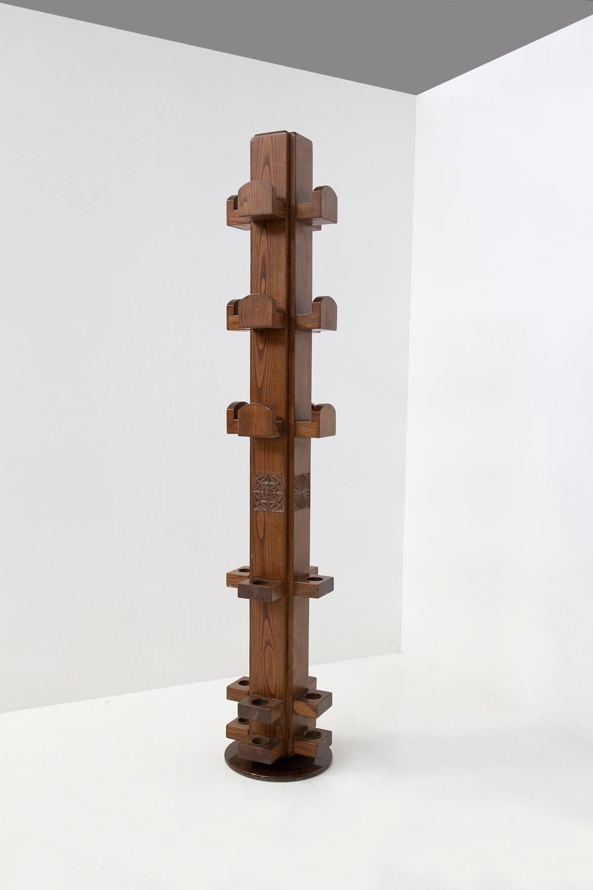 Imposing and important clothes rack totem designed by Giuseppe Rivadossi in the 1970s. The entire garment rack is made of carved and patinated Oak Wood, polished finish. At the base we have a very solid painted metal plate that acts as a pivot to