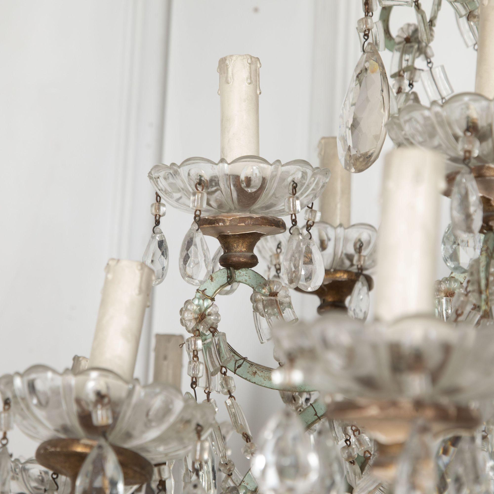 Impressive Italian Louis XV-style cut-glass chandelier.
With a subtle Eau De Nil iron frame. The many arms are joined by layers of intersecting swags of flat crystals and beads.
With a turned giltwood finial to the center, top, and beneath each