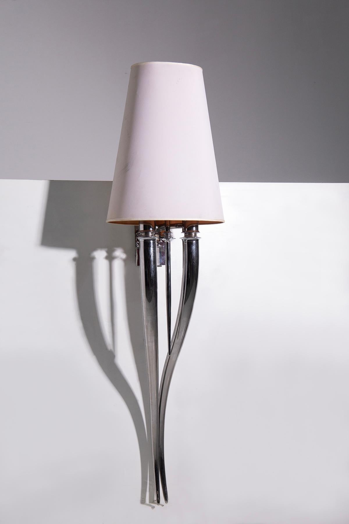 A magnificent Italian Deco-style wall lamp from the 1980s, this elegant piece showcases the timeless elegance and intricate artistry of the Art Deco style with the modernity of the 1980s. The lamp's structure features a sturdy nickel-plated brass